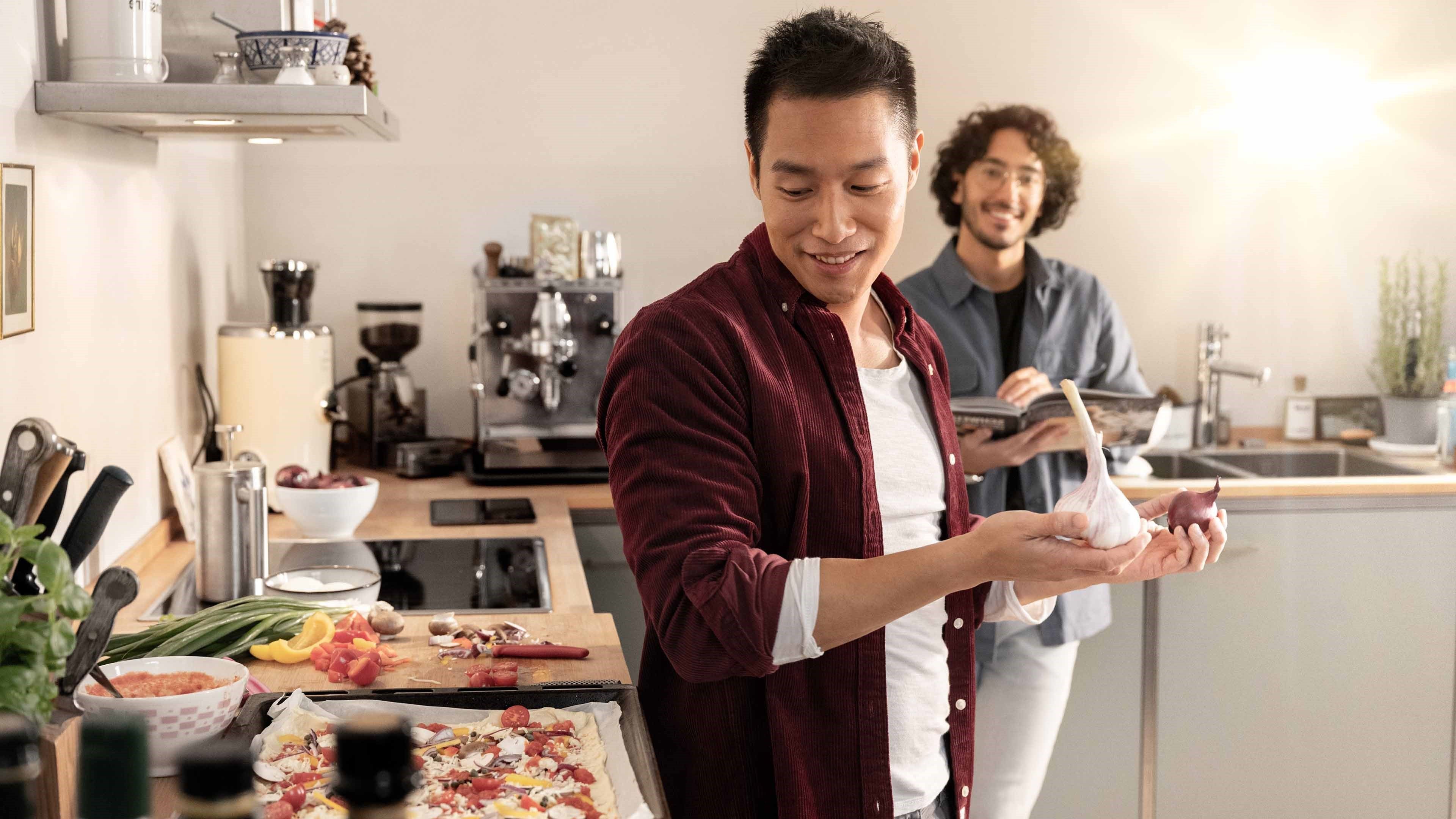Zwei Männer bereiten gemeinsam Pizza zu