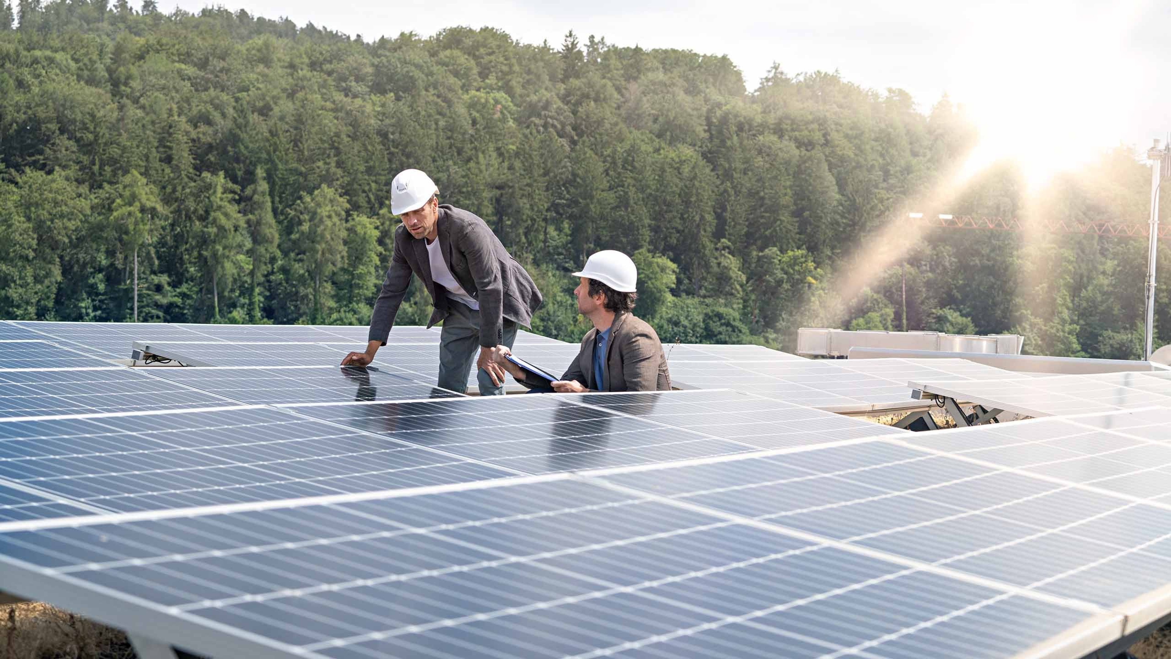 Zwei Handwerker installieren eine Photovoltaik-Anlage. 