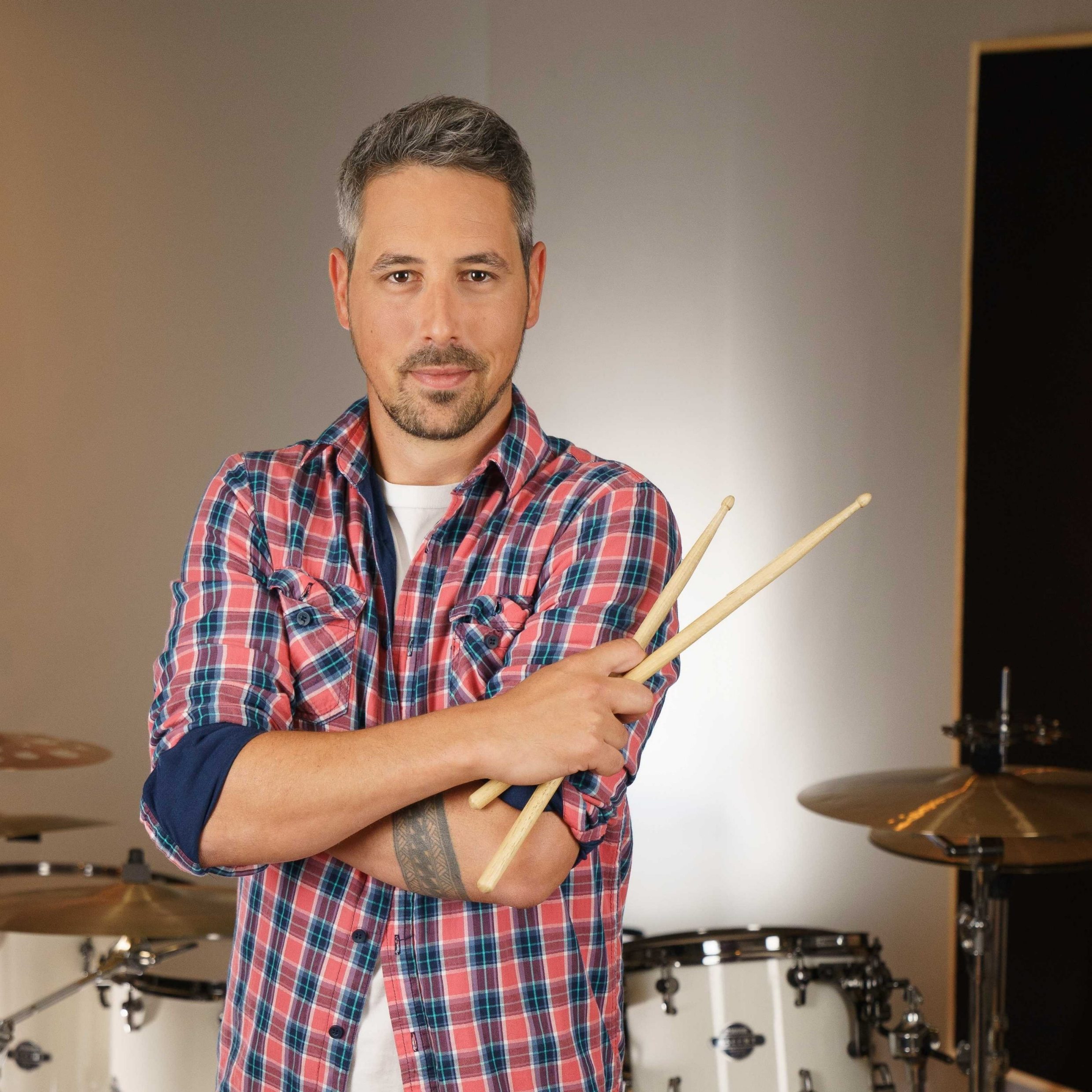 Dominik Mäder, Mitarbeiter von Swiss Life, hält zwei Drumsticks und blickt in die Kamera
