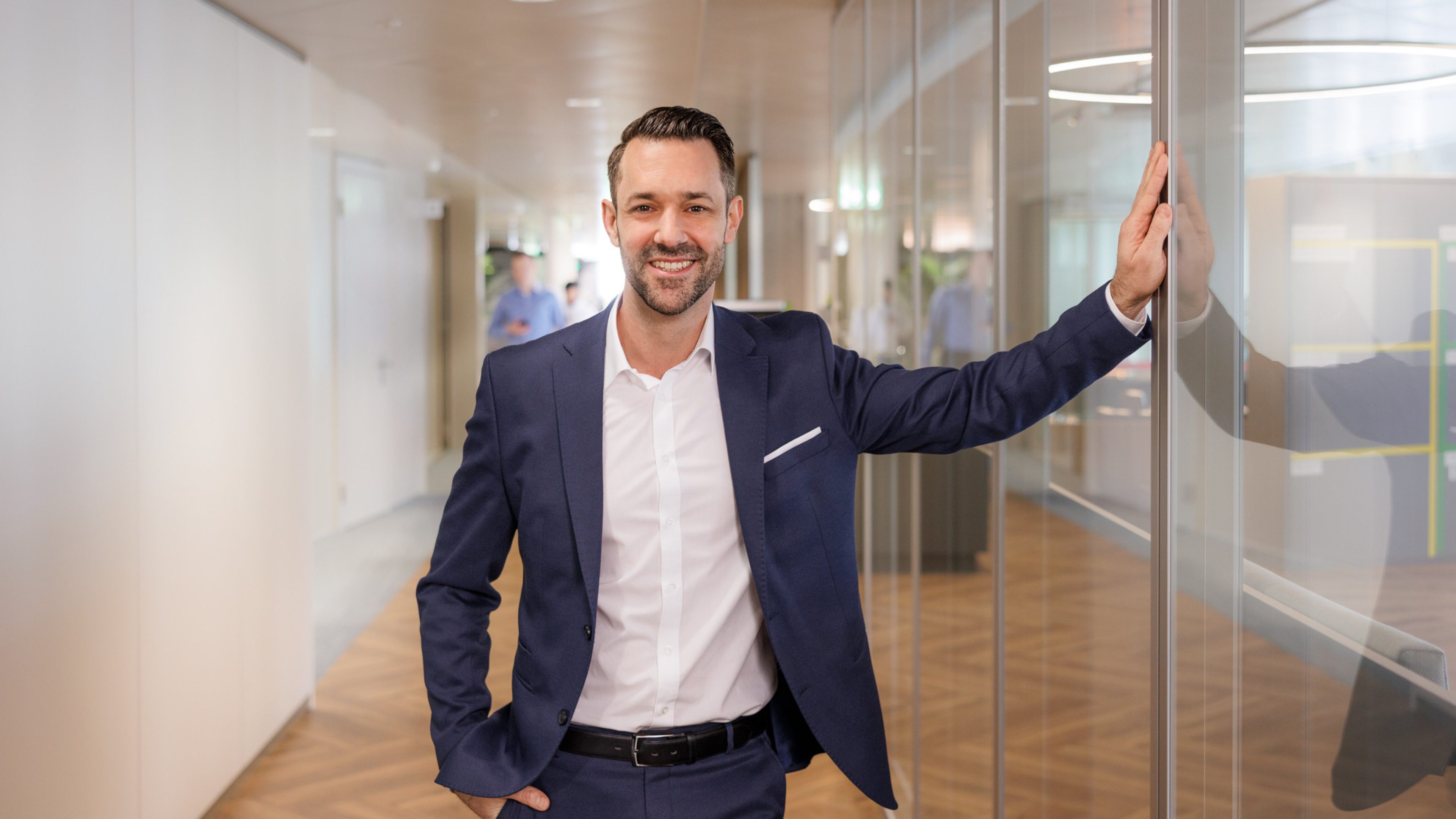 Mitarbeiter von Swiss Life in einem modernen Büro, der direkt in die Kamera lächelt. 