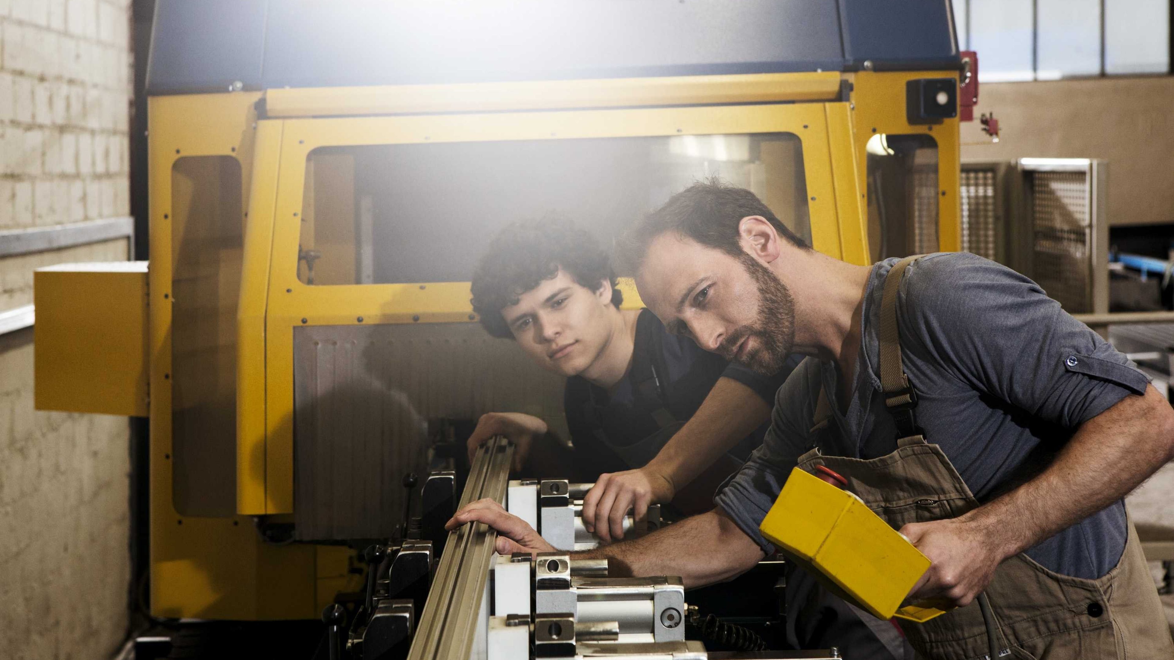 Zwei Arbeitskollegen prüfen eine Maschine in ihrer Werkstatt. 