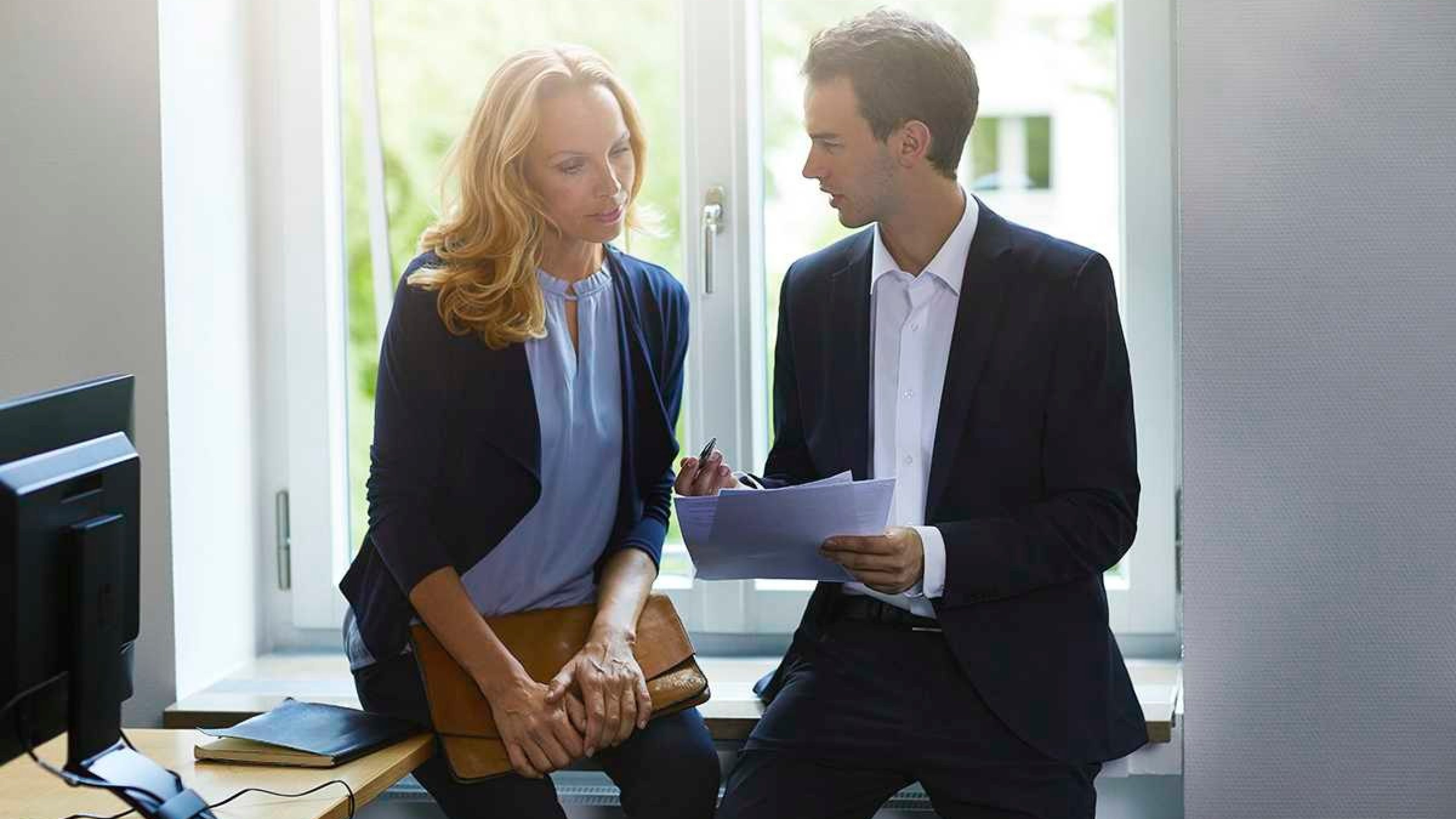 Zwei Arbeitskollegen sitzen im Büro und besprechen betriebliches Gesundheitsmanagement.