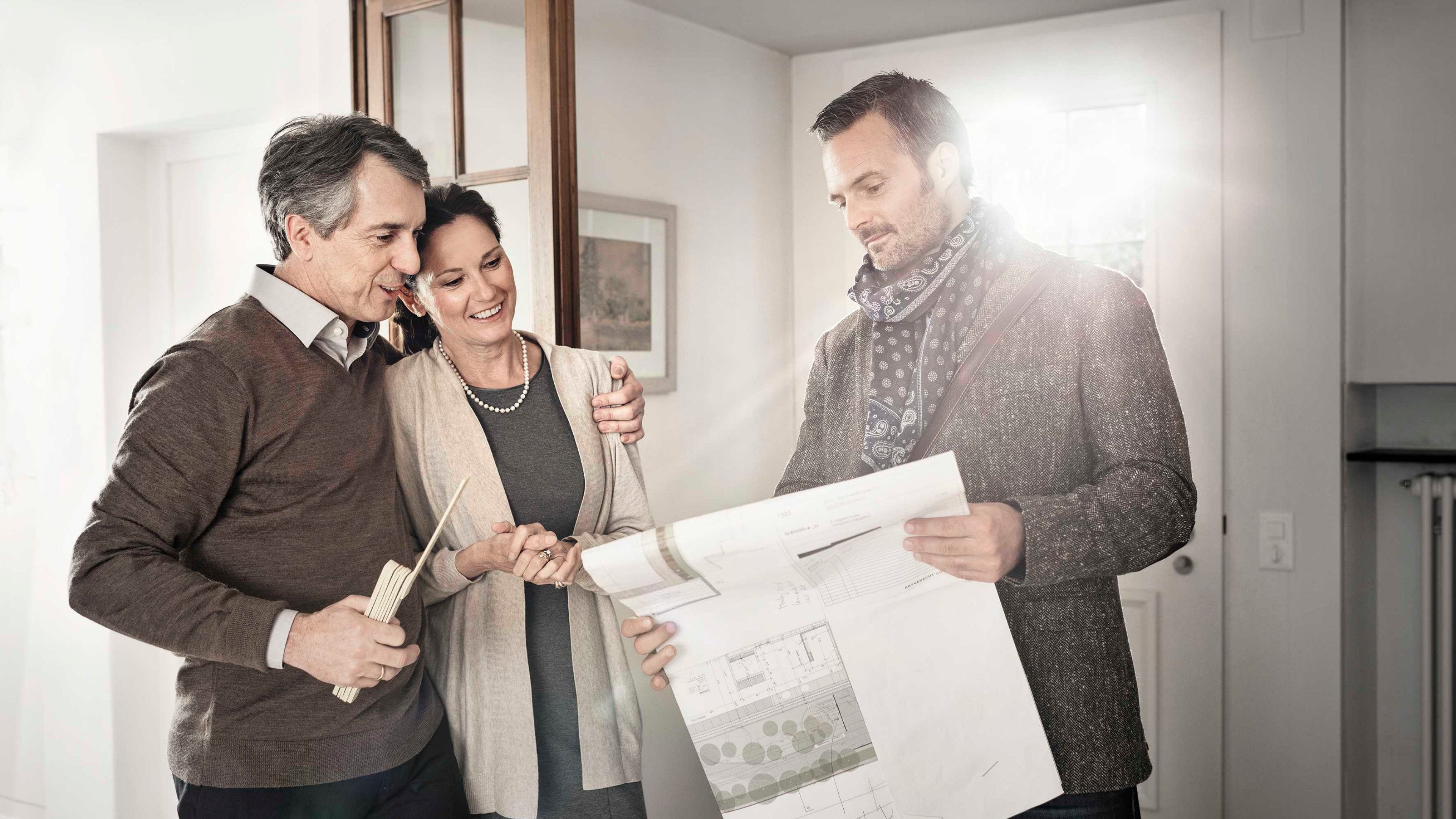 Ein Berater zeigt einem Paar einen Bauplan in ihrem Zuhause.