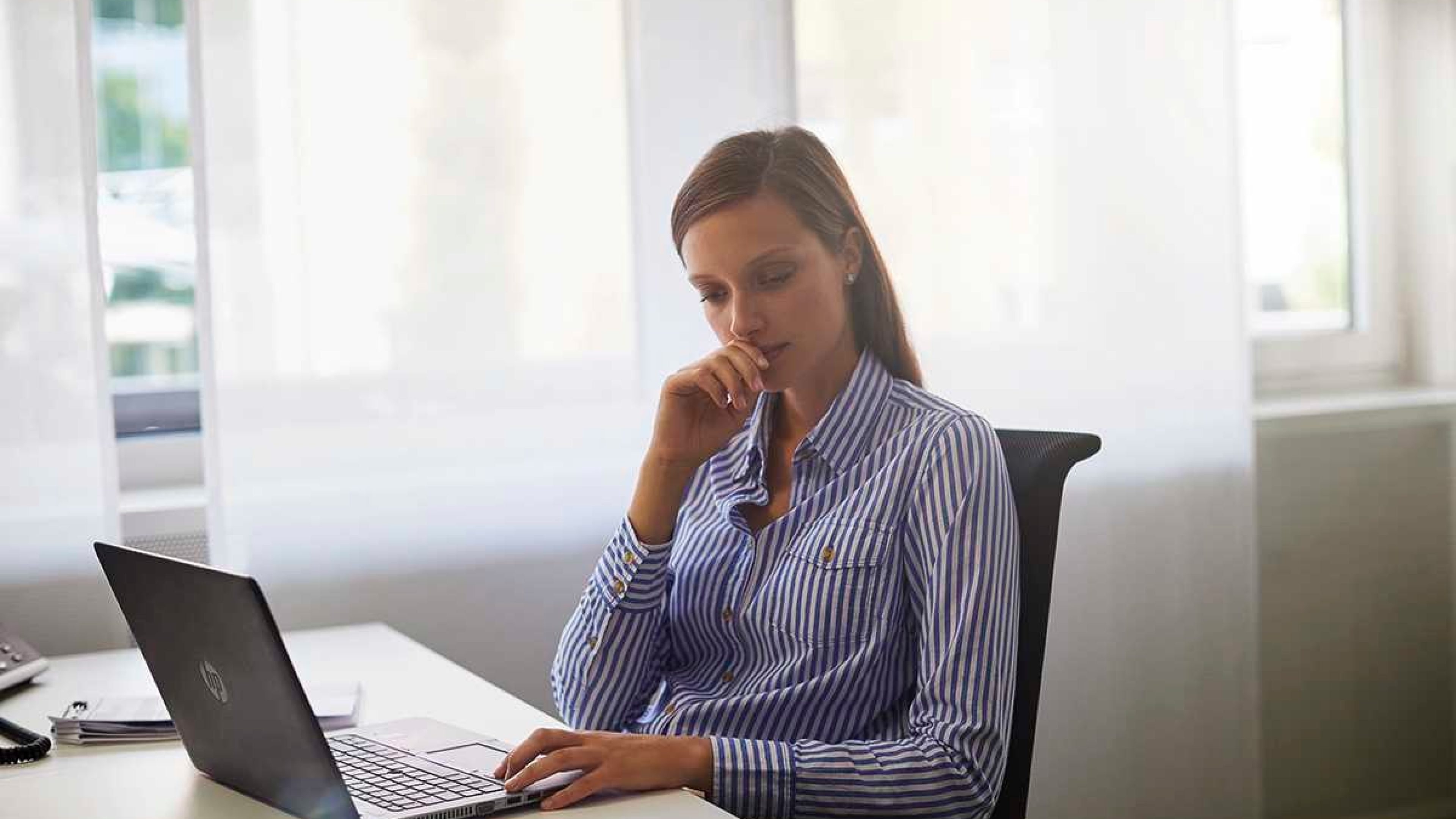 Eine Frau sitzt am Schreibtisch und informier sich am Labtop zu BGM-Online-Seminaren.