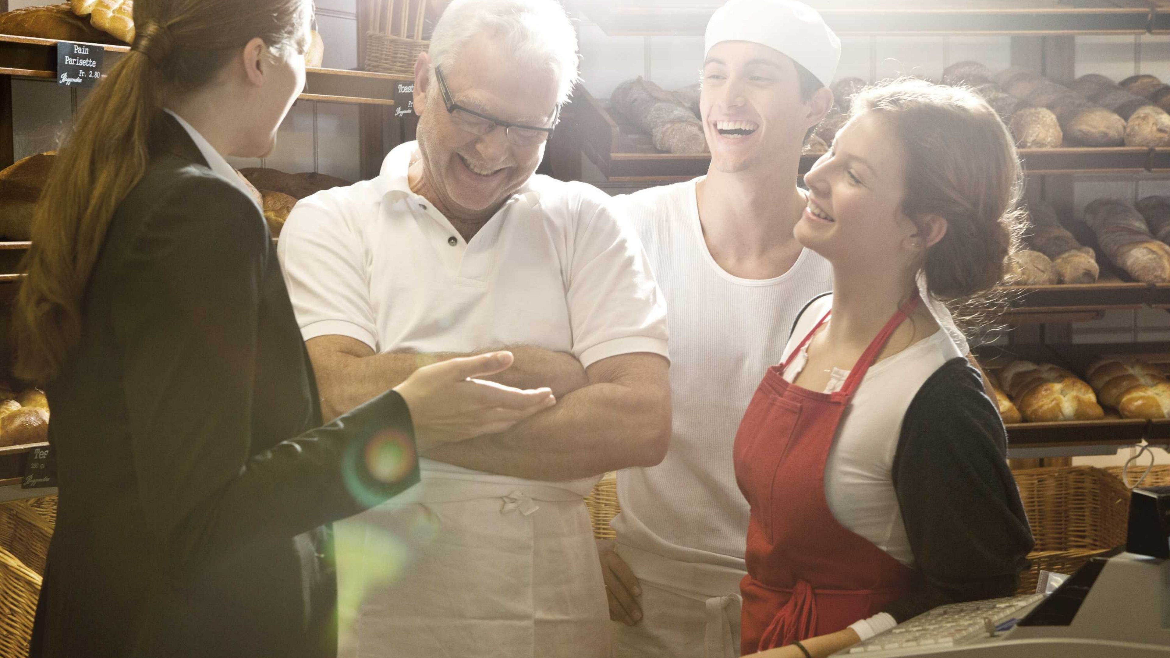 Mitarbeitende einer Bäckerei unterhalten sich in der Backstube mit einer Beraterin.