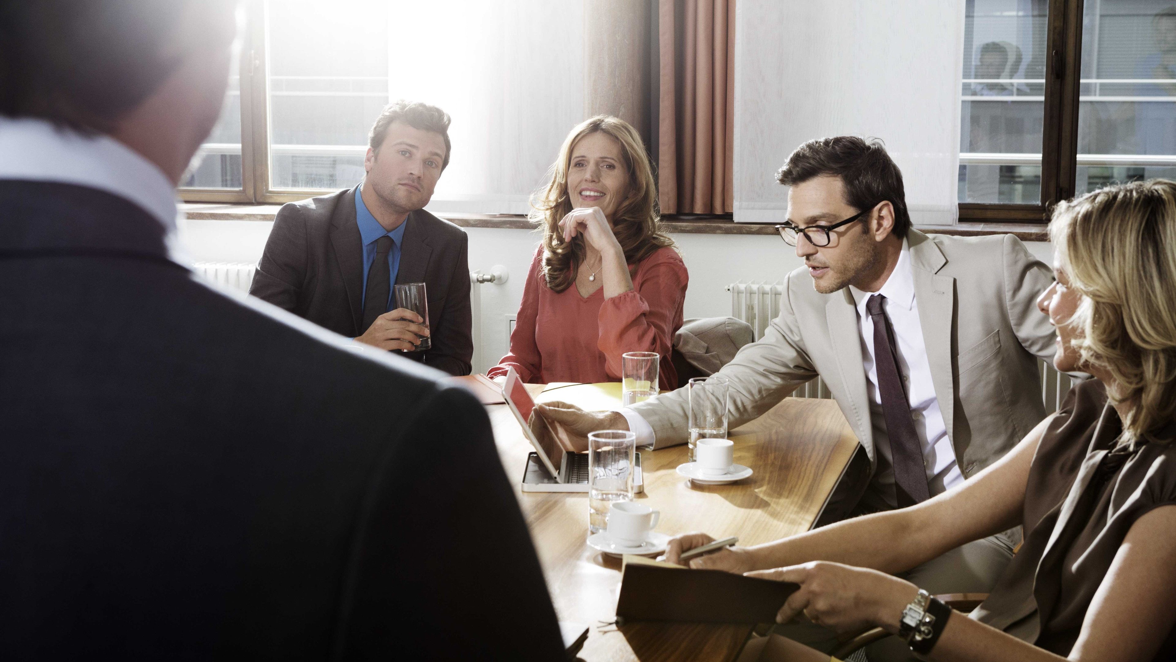 Mehrere Arbeitskollegen sitzen an einem Tisch und besprechen die firmeneigene Stiftung. 