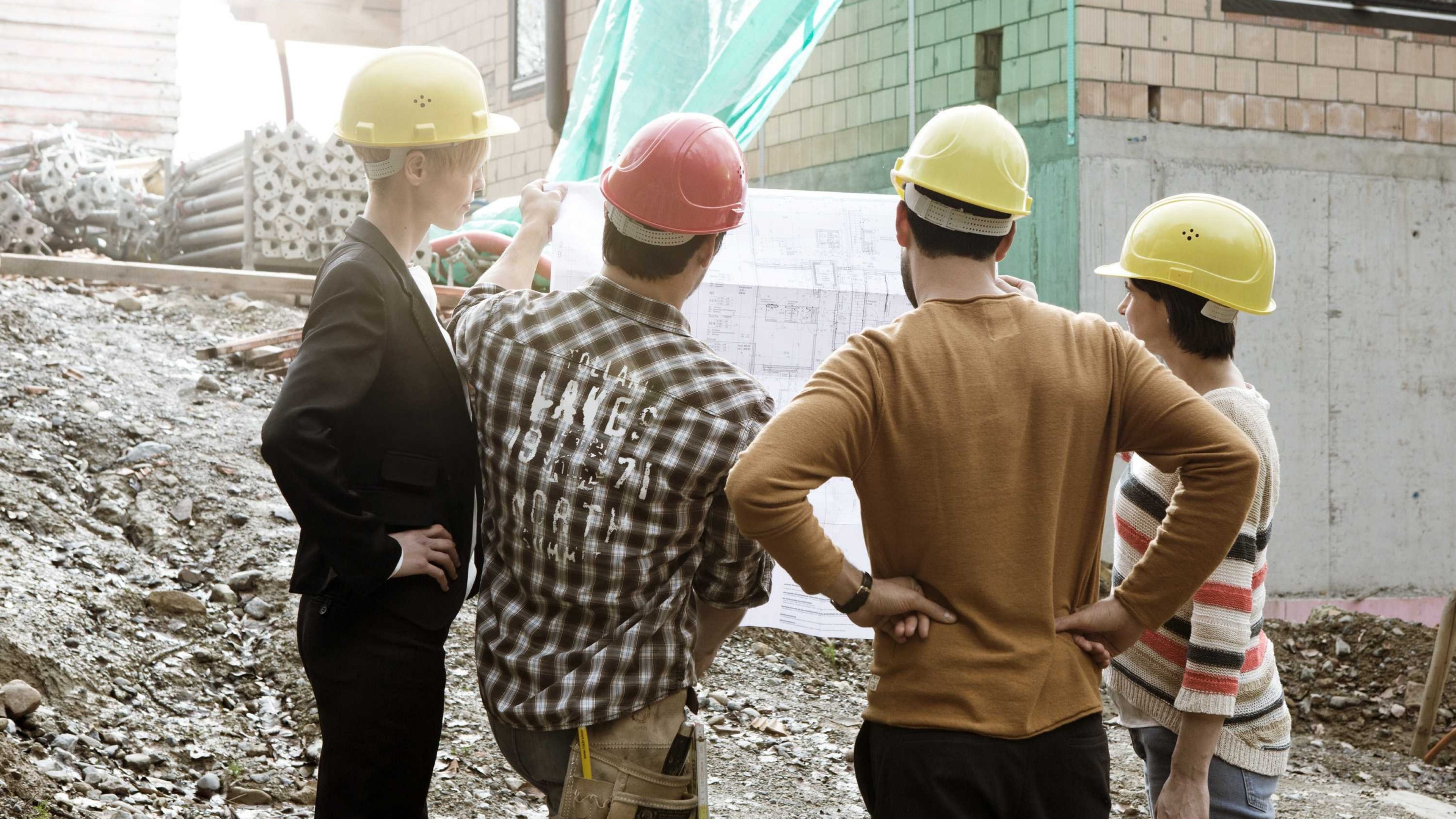 Eigentümer studieren einen Bauplan auf der Baustelle des künftigen Eigenheims.