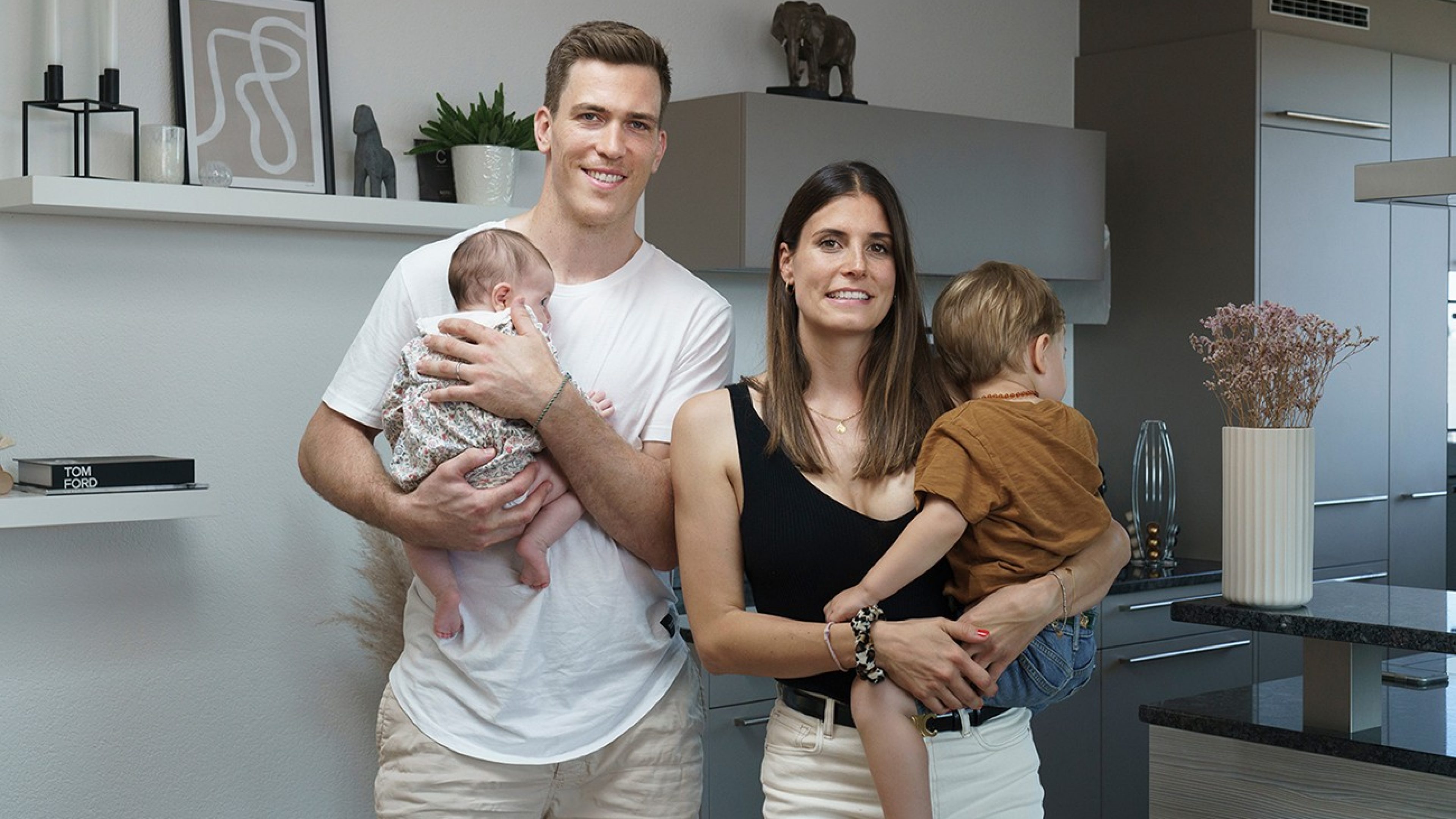 Parents standing in a kitchen with their children.