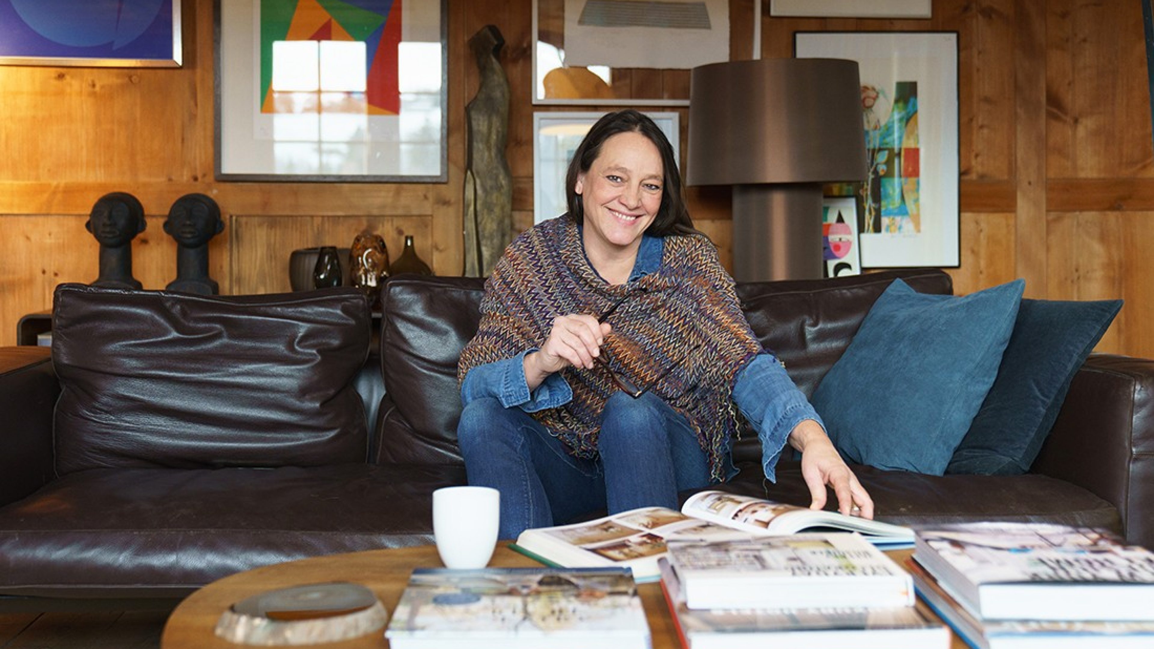 A woman sits on a leather sofa in a living room.