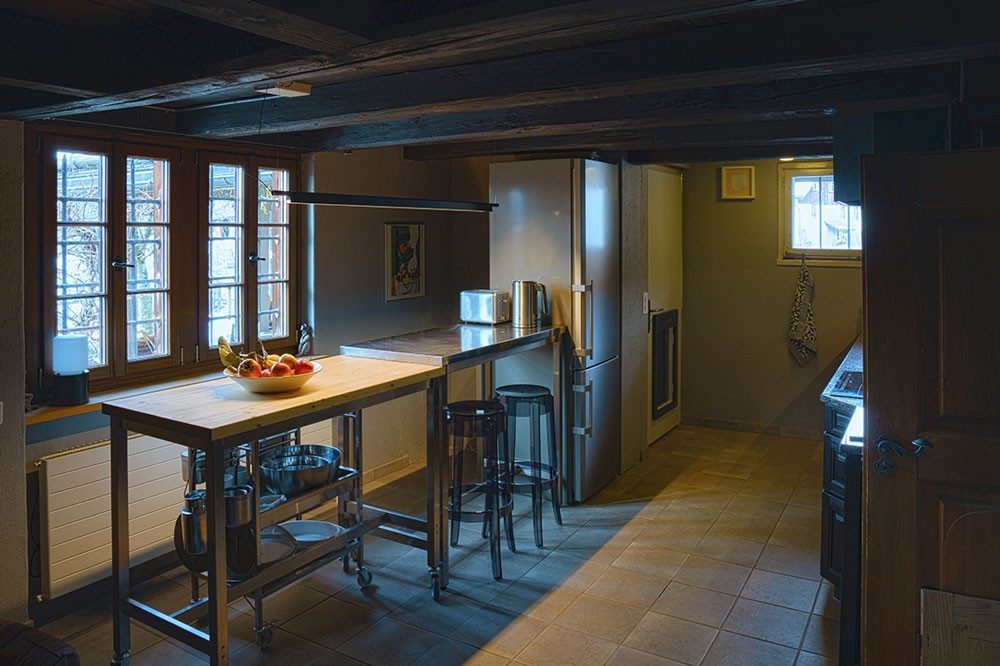 A high table with fruit stands next to the kitchen units.