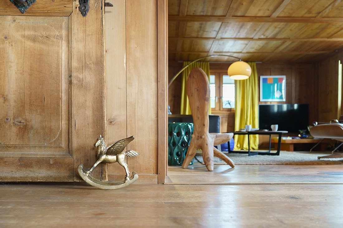 A living room with wooden ceiling and wooden floorboards with various decorative elements.