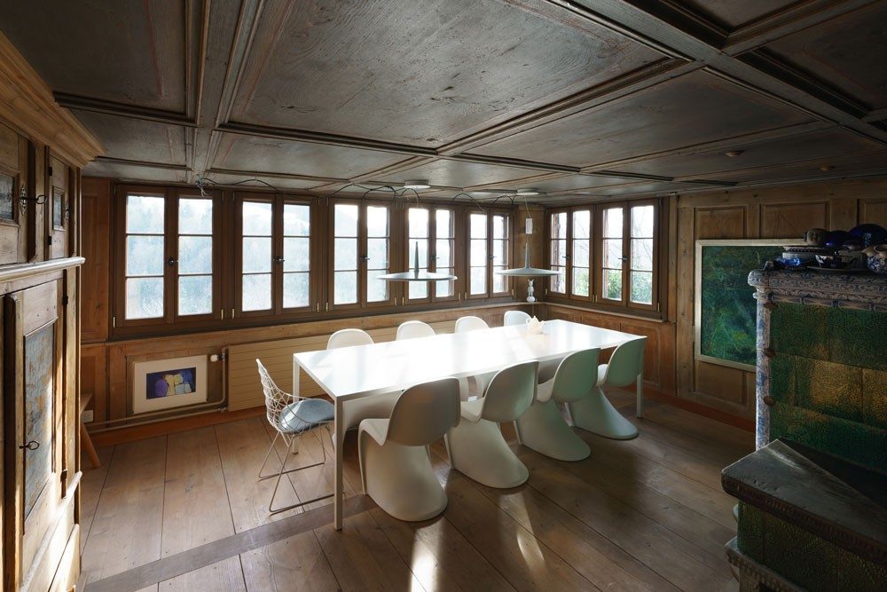 A white table in a wood-panelled room with modern art on the walls.
