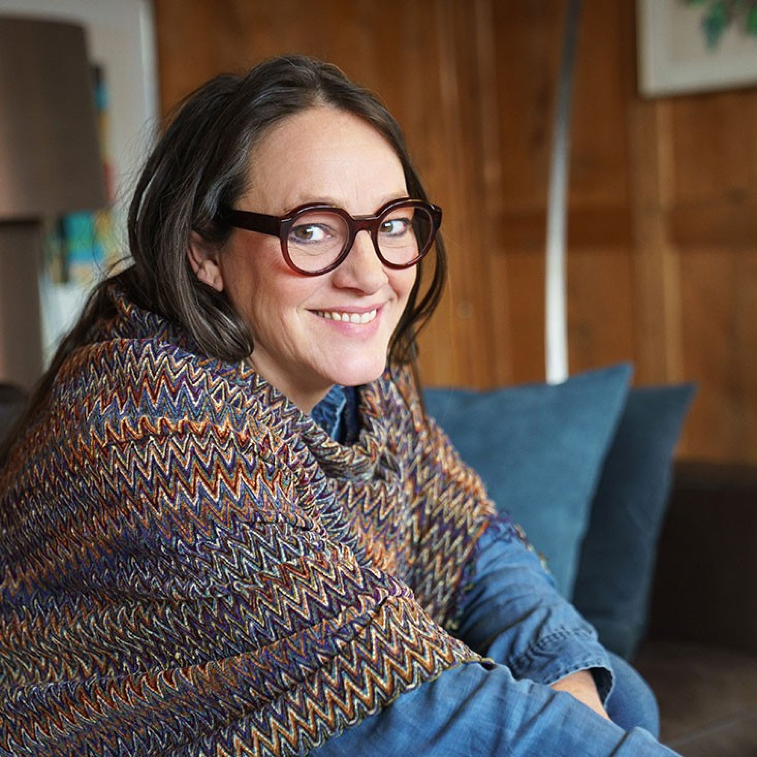 A woman with glasses smiles at the camera.