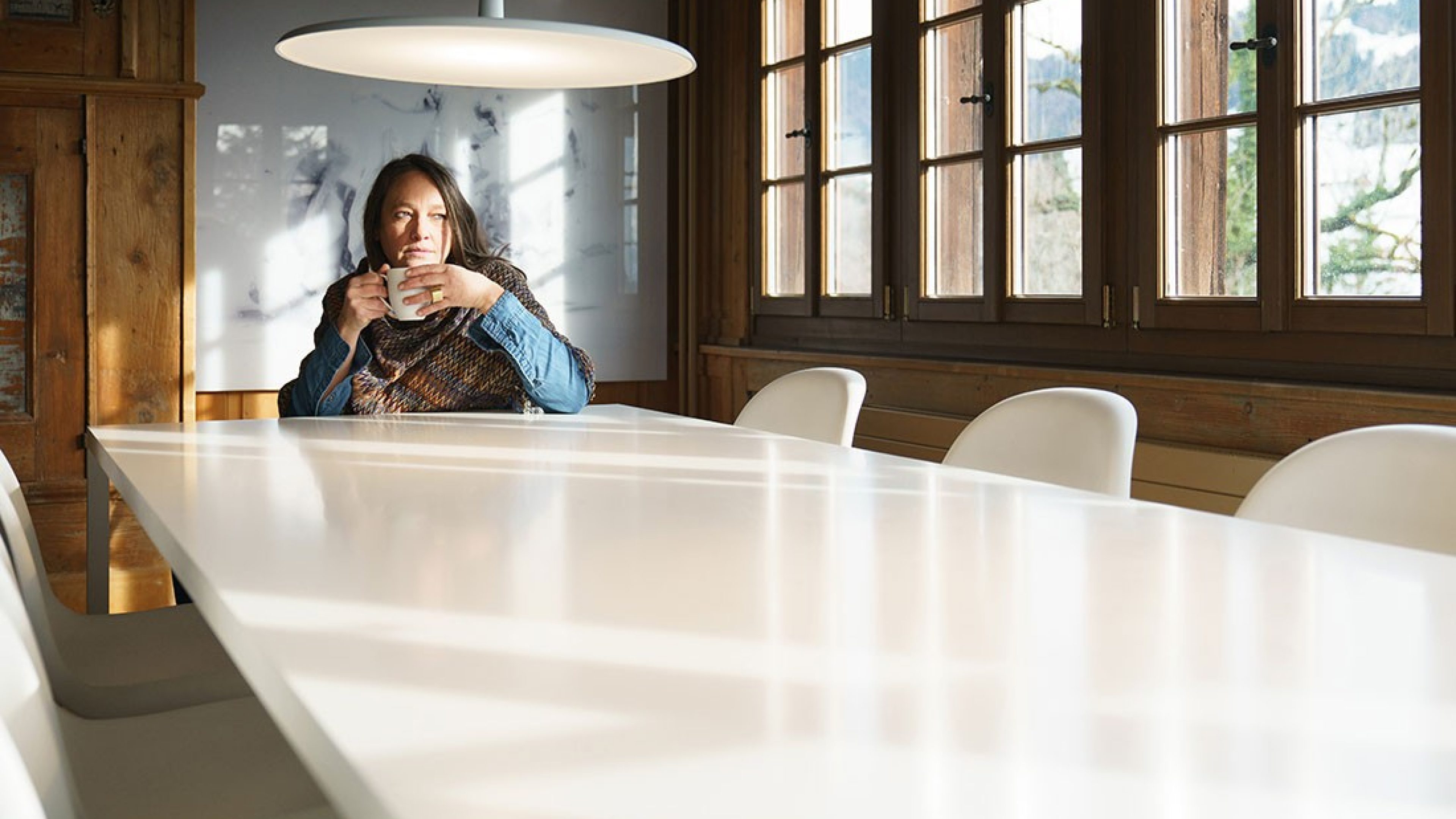 A woman sits at a table and looks out of the window.