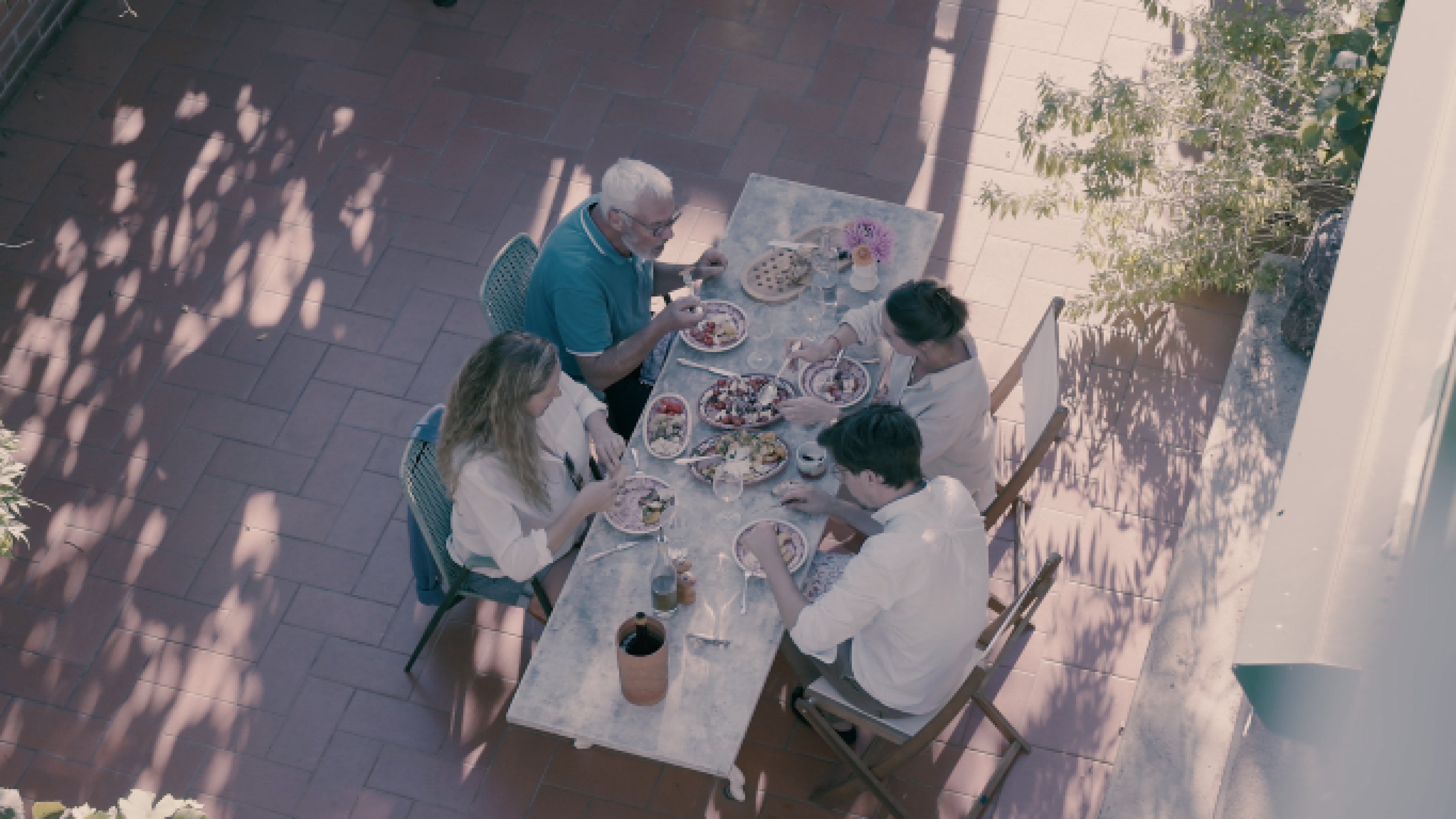 Four people are sitting on the terrace enjoying a meal.