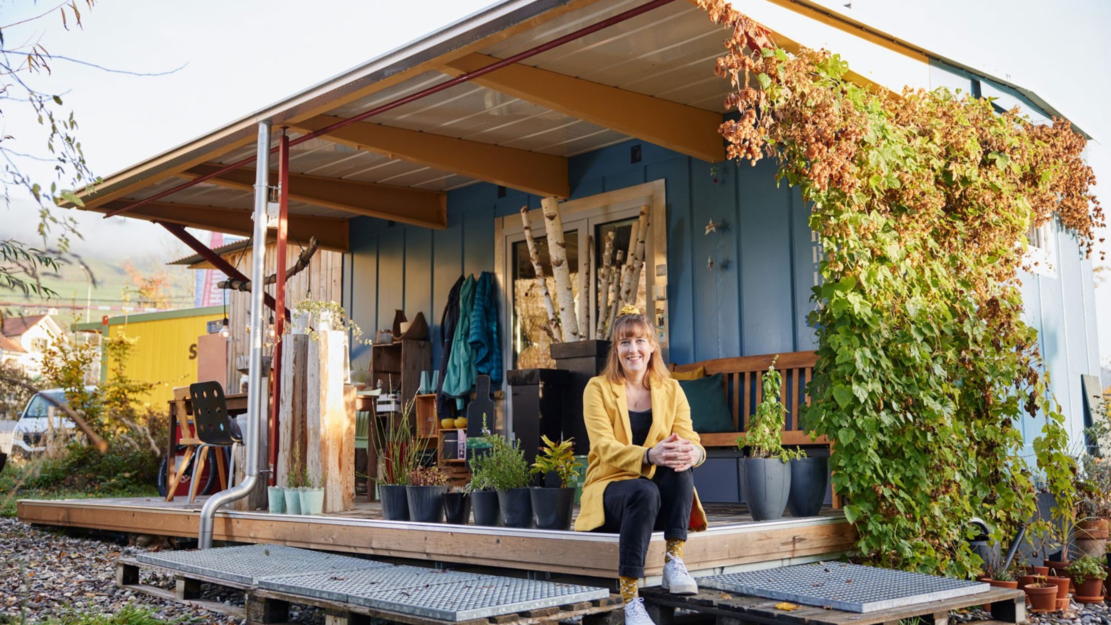 A woman sits in front of a tiny house