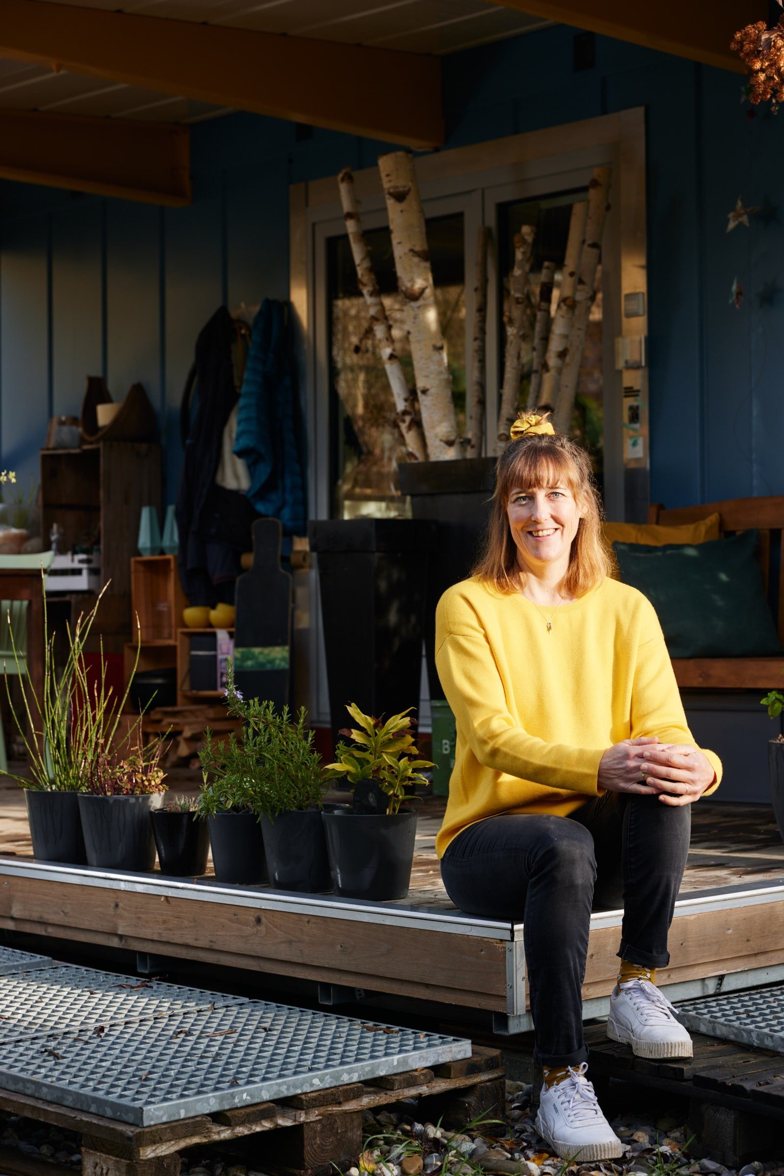 A woman sits in front of a tiny house