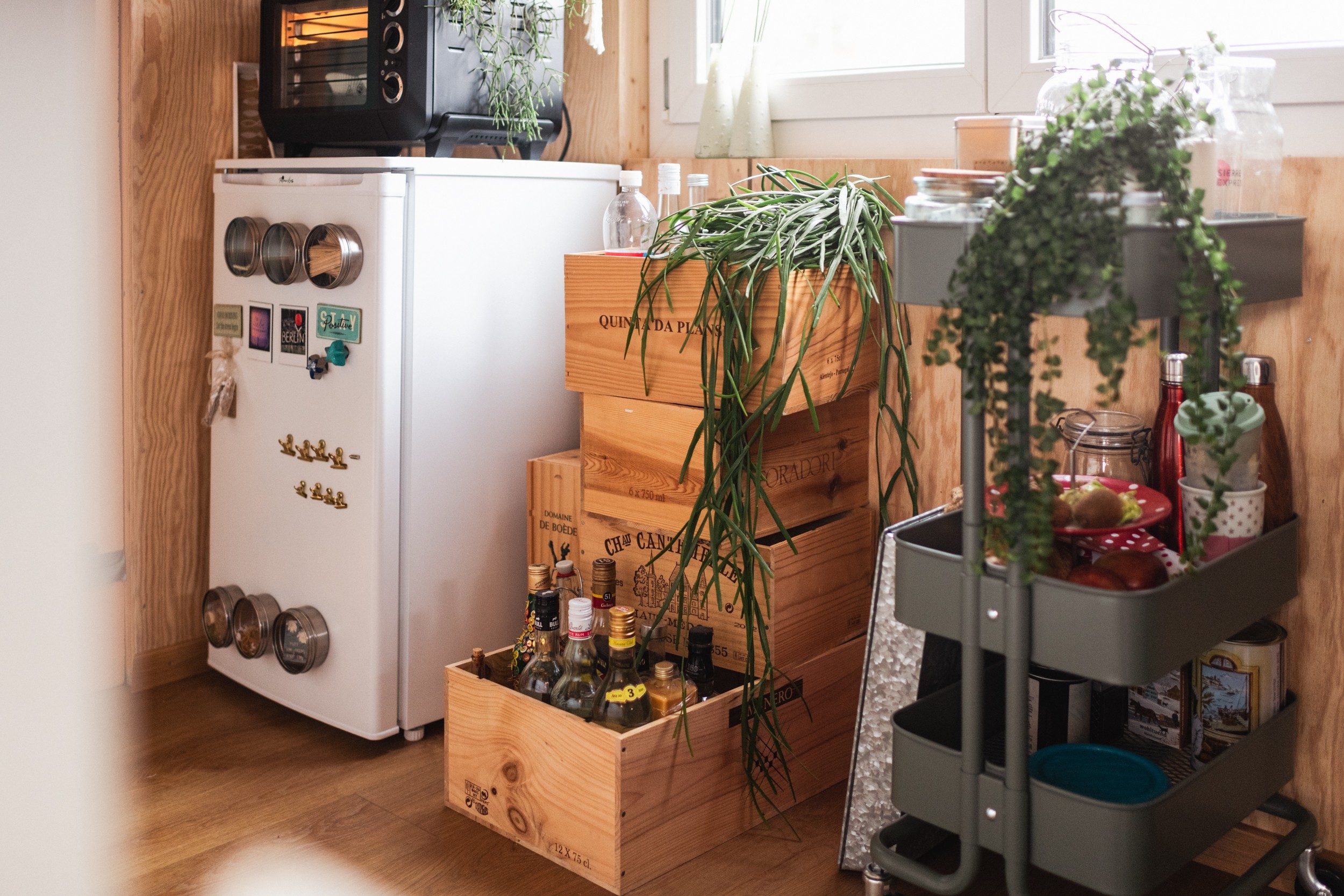 A fridge, a bar made of old wine crates and a serving trolley are by a window