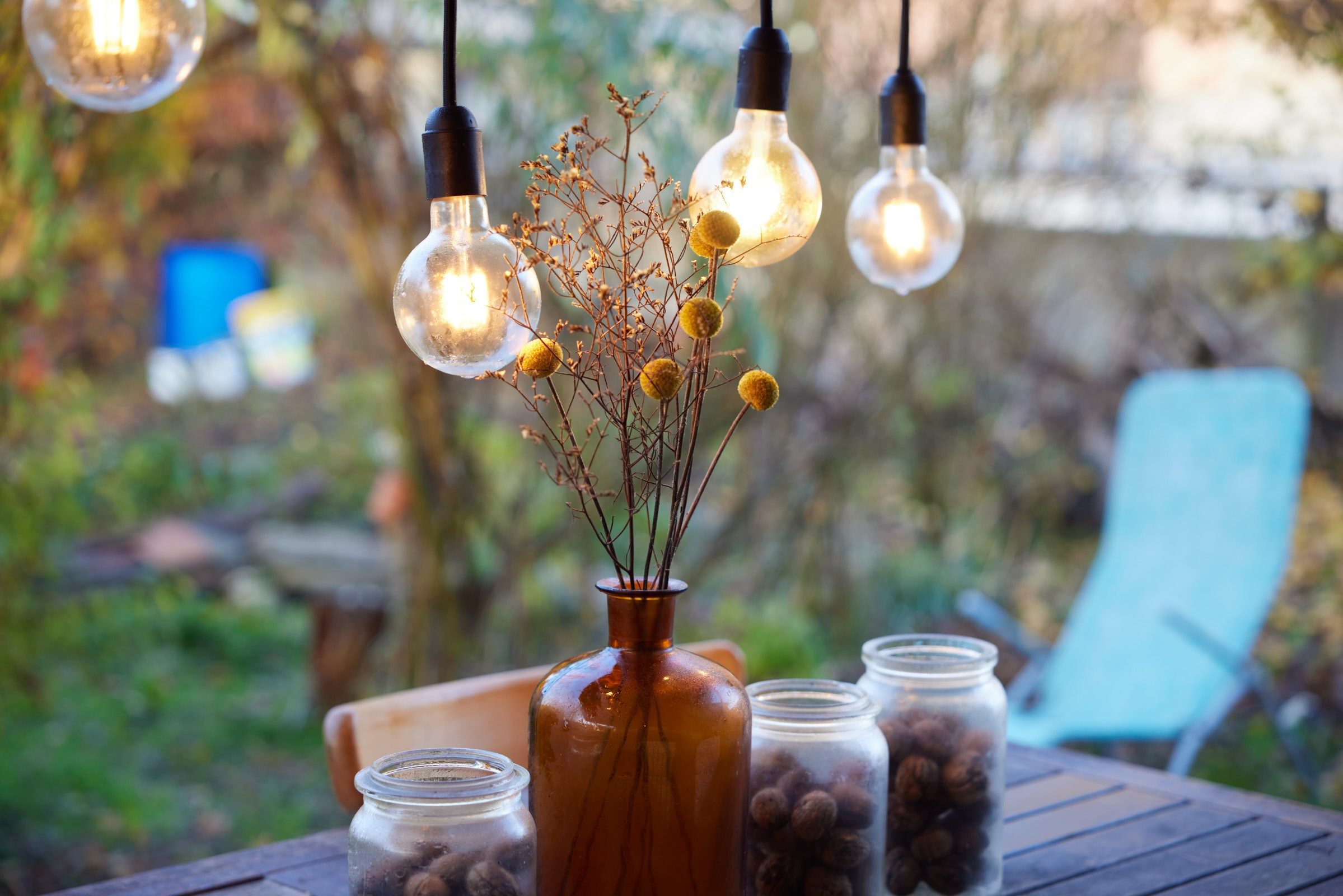 Three lamps hang over a beautifully decorated garden table