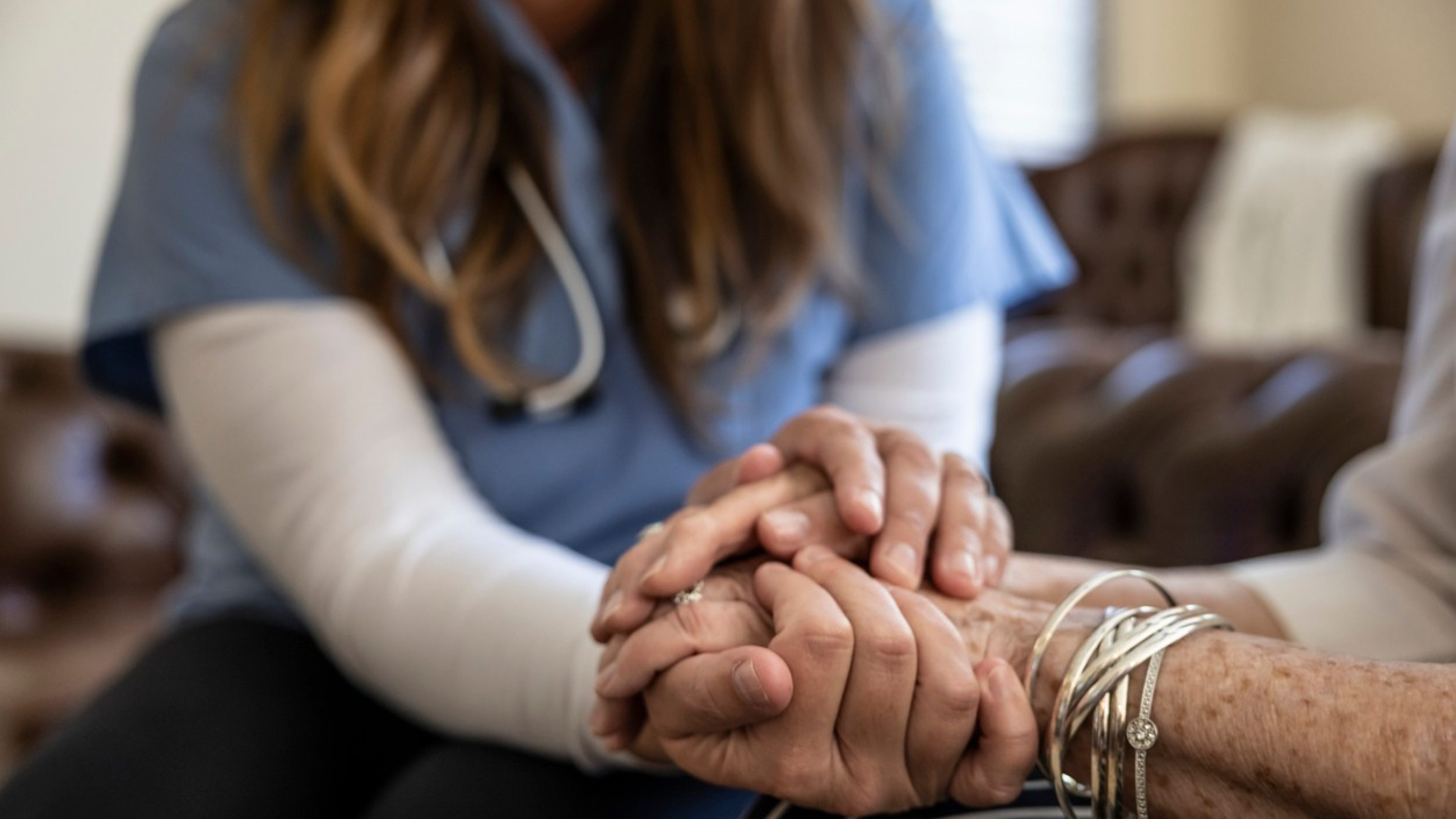 Nurse holds a patient’s hands.