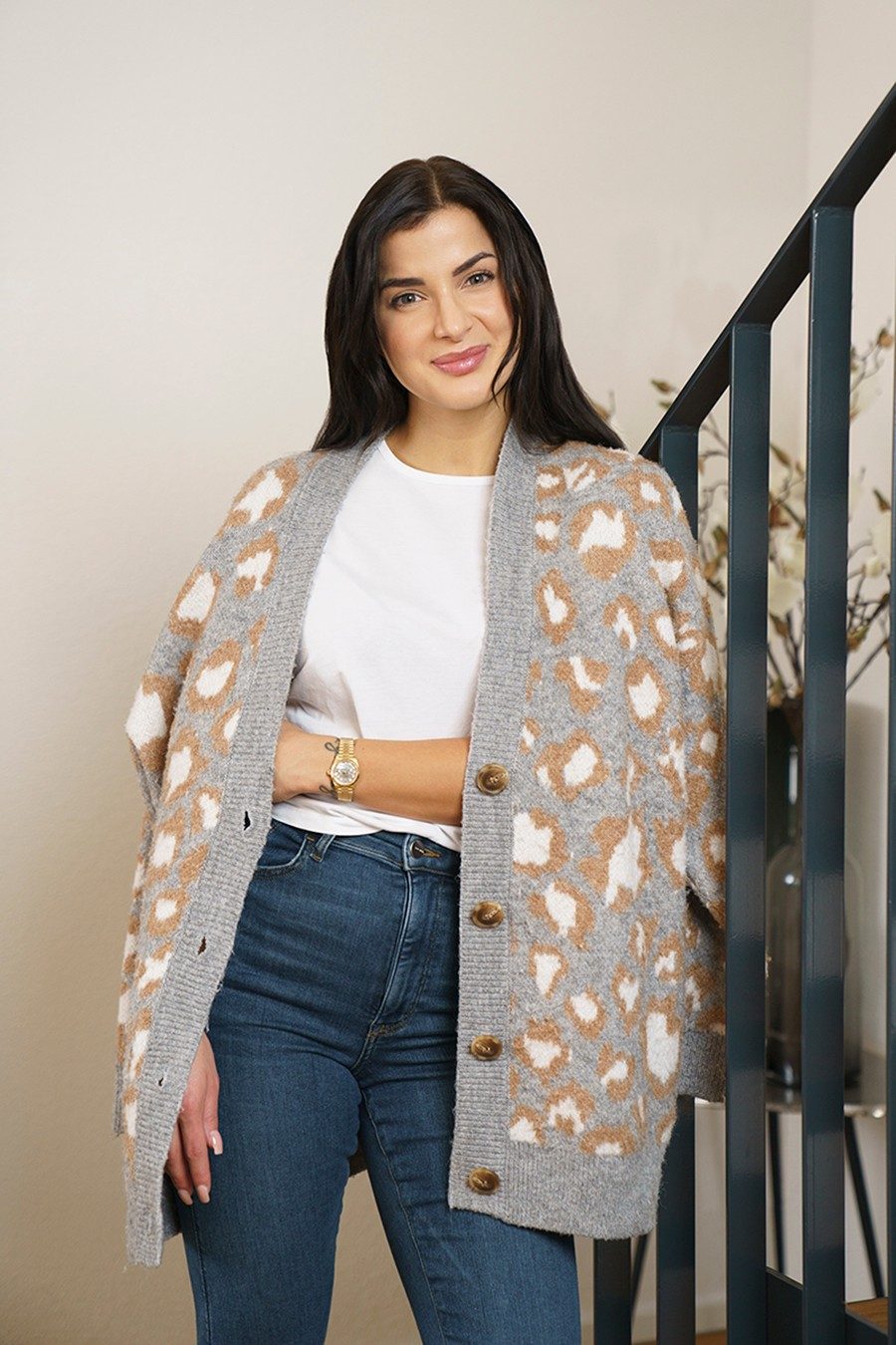 A woman wearing a patterned cardigan smiles into the camera.