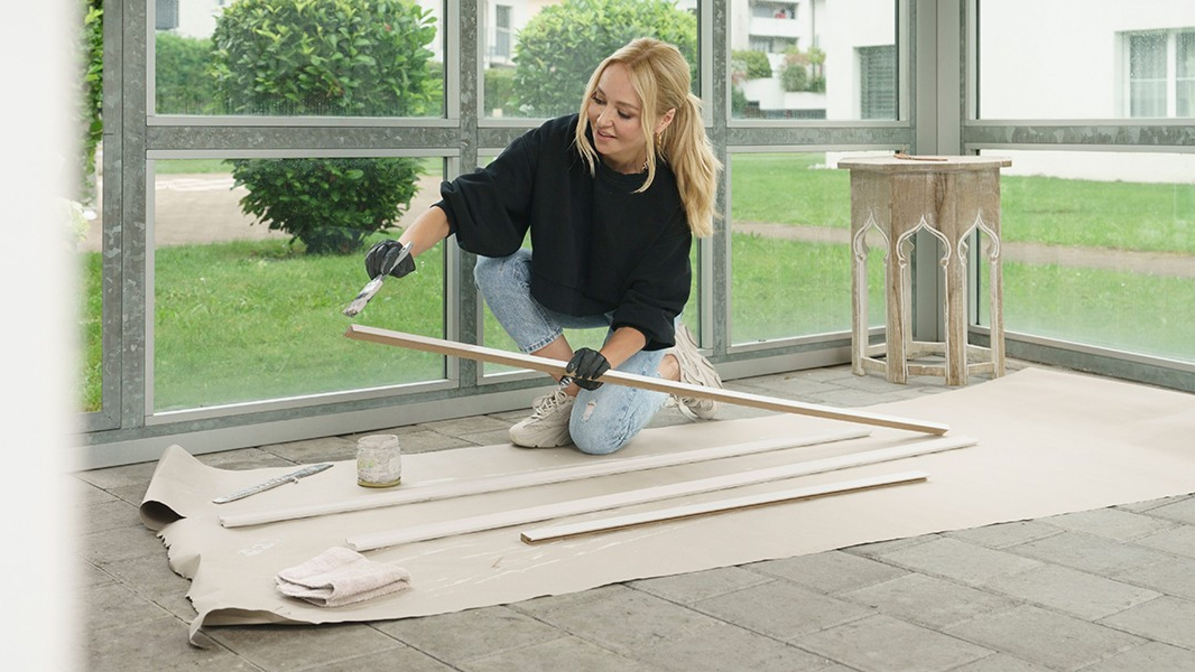 Woman kneeling on the floor painting a skirting board. 