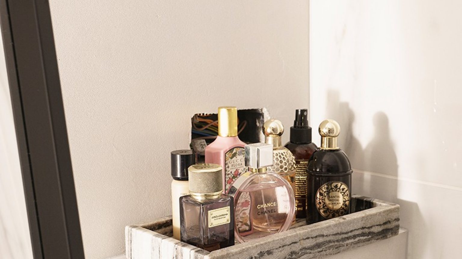 On a shelf in the bathroom is a tray with different perfume bottles.