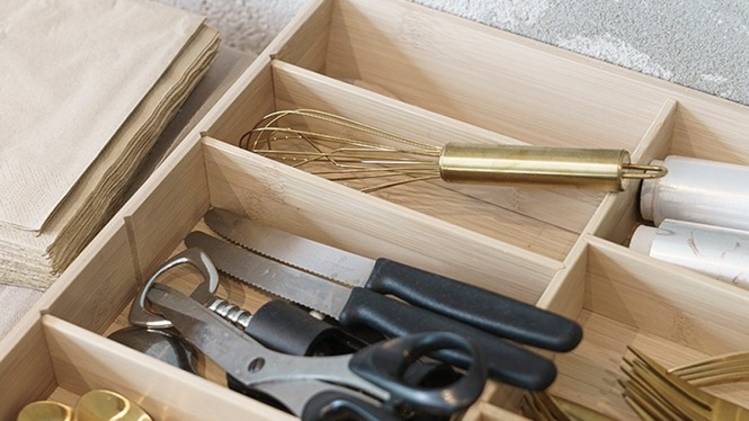 A cutlery box with gold-coloured cutlery and other kitchen utensils.