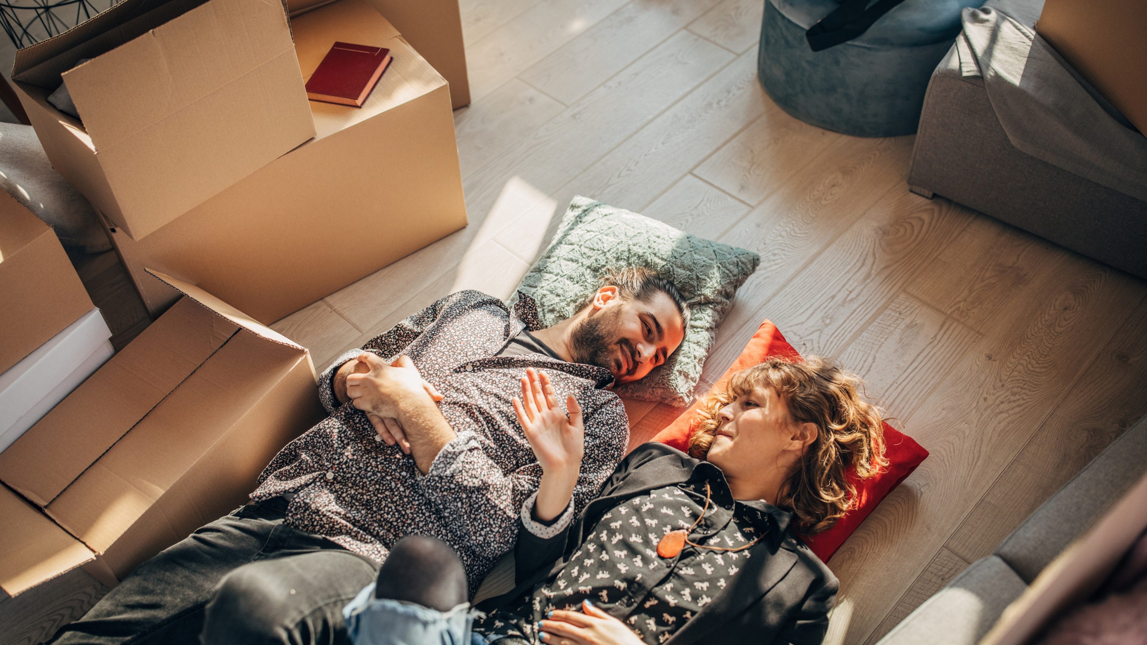 Man and woman, young couple moving into their new apartment together, lying on the floor together.