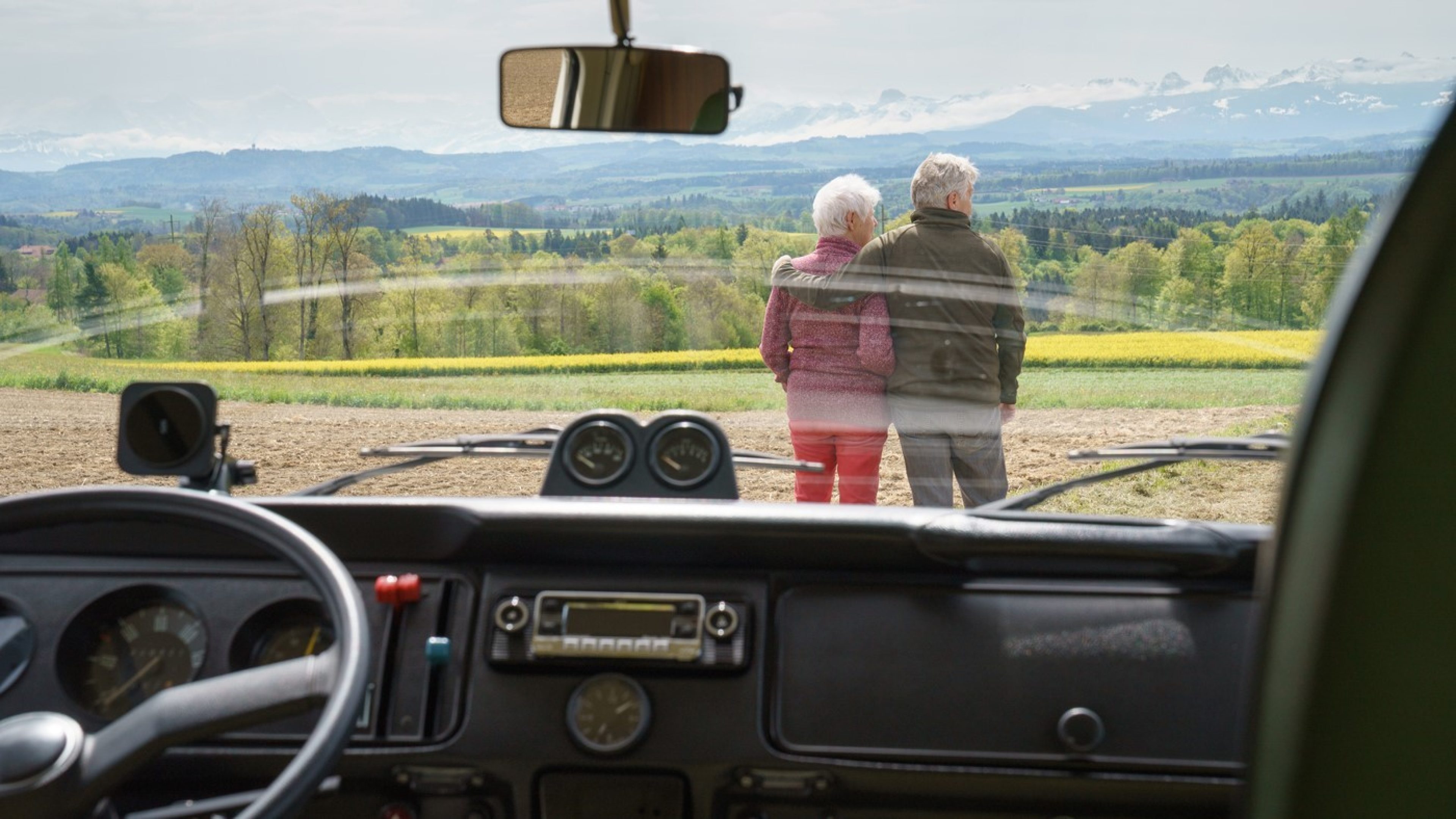 From the VW van, standing between the driver and passenger seats, you can see the landscape through the front window.  Kurt has his arm around Monica as they look at the mountain range in front of them.