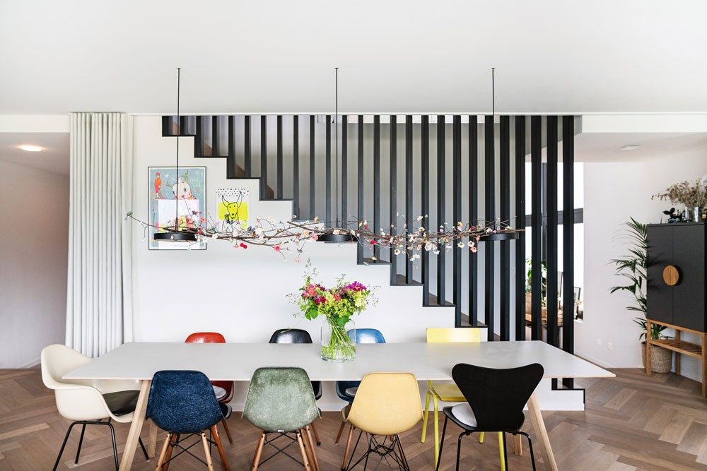 A long table in a living room with elegant Eames chairs by Vitra around it.