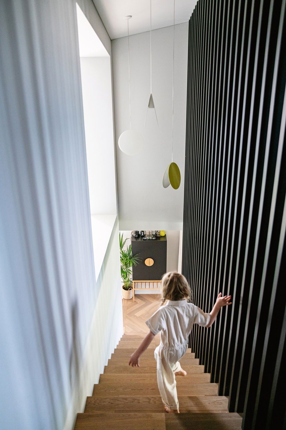 A child runs downstairs, holding the railings.