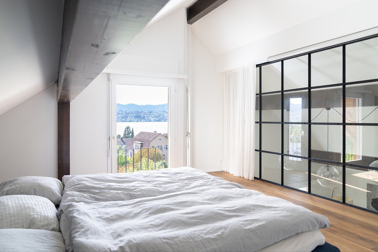 The bed faces a large glass front and the room has a view of Lake Zurich