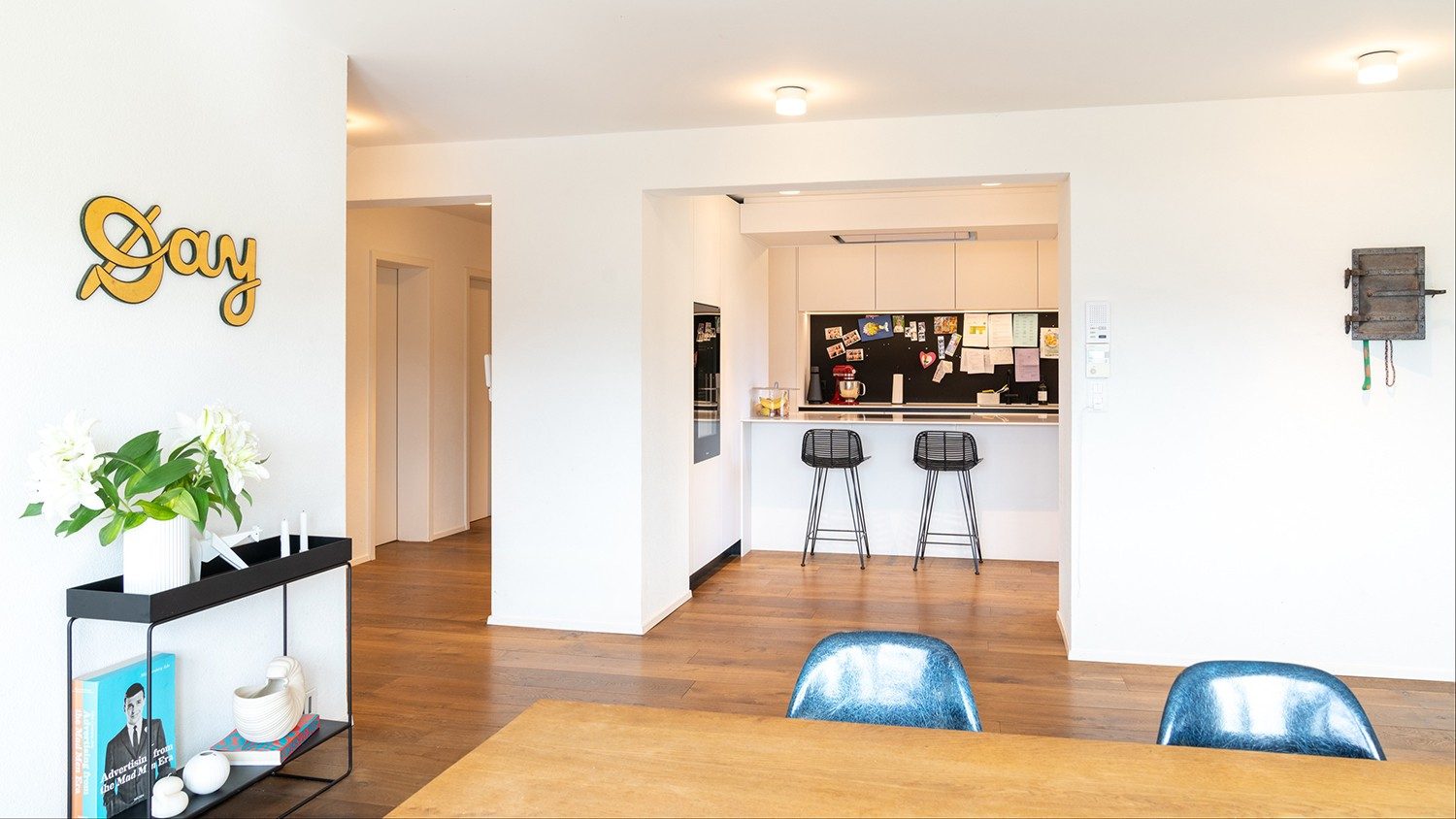 The kitchen has high bar stools, next to it hangs the antique key-box