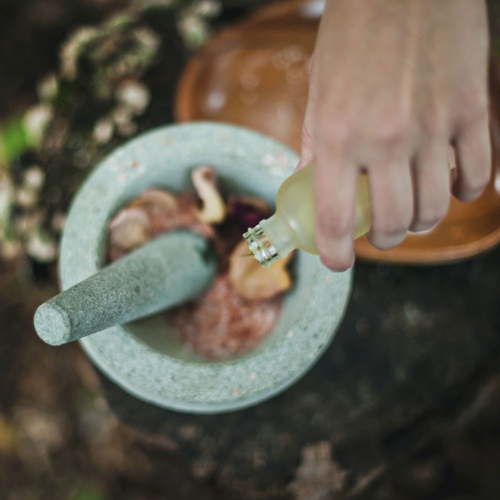 Essential oil being poured into a mortar and pestle.