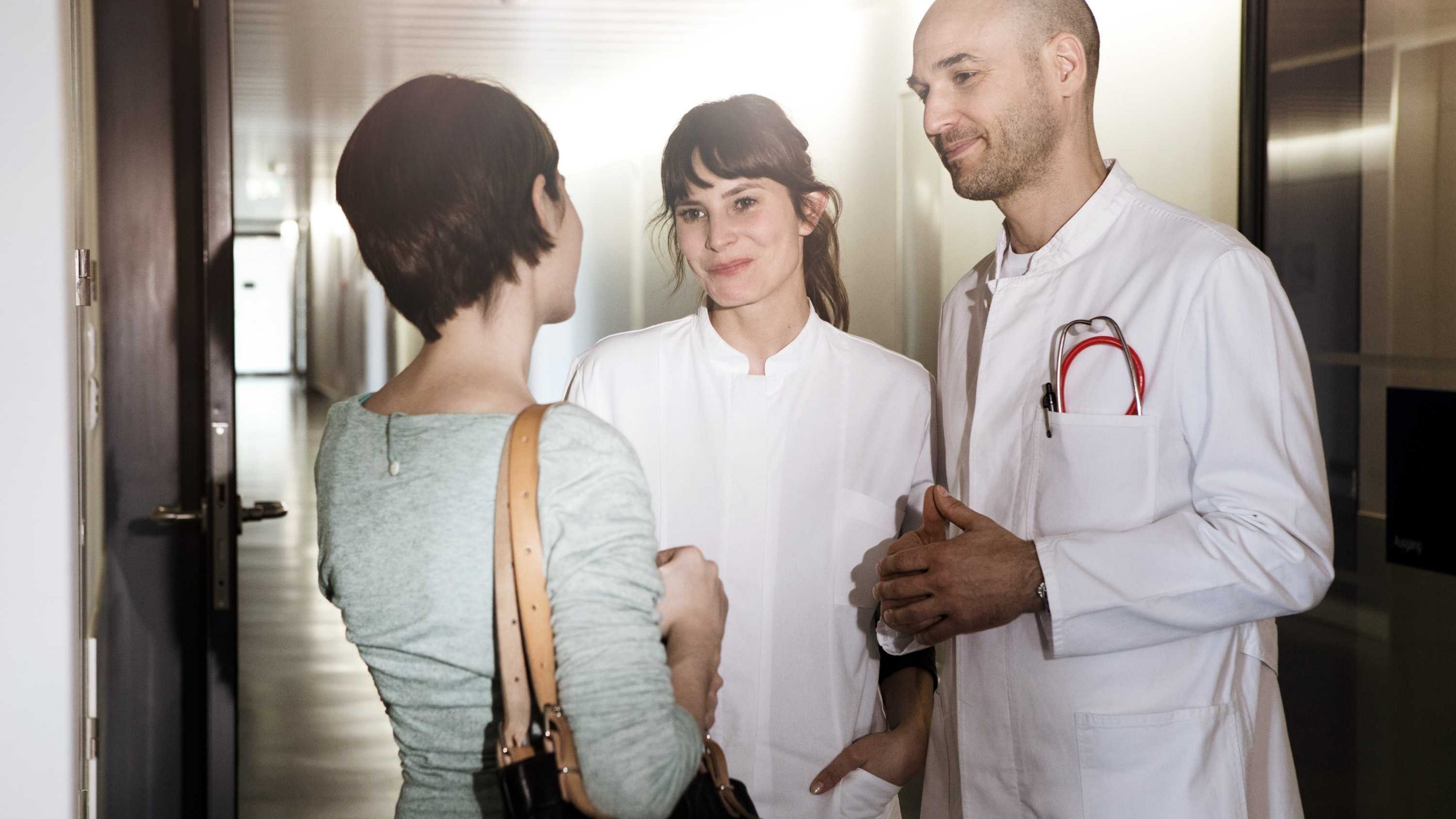 A woman is talking to medical professionals in a hospital.