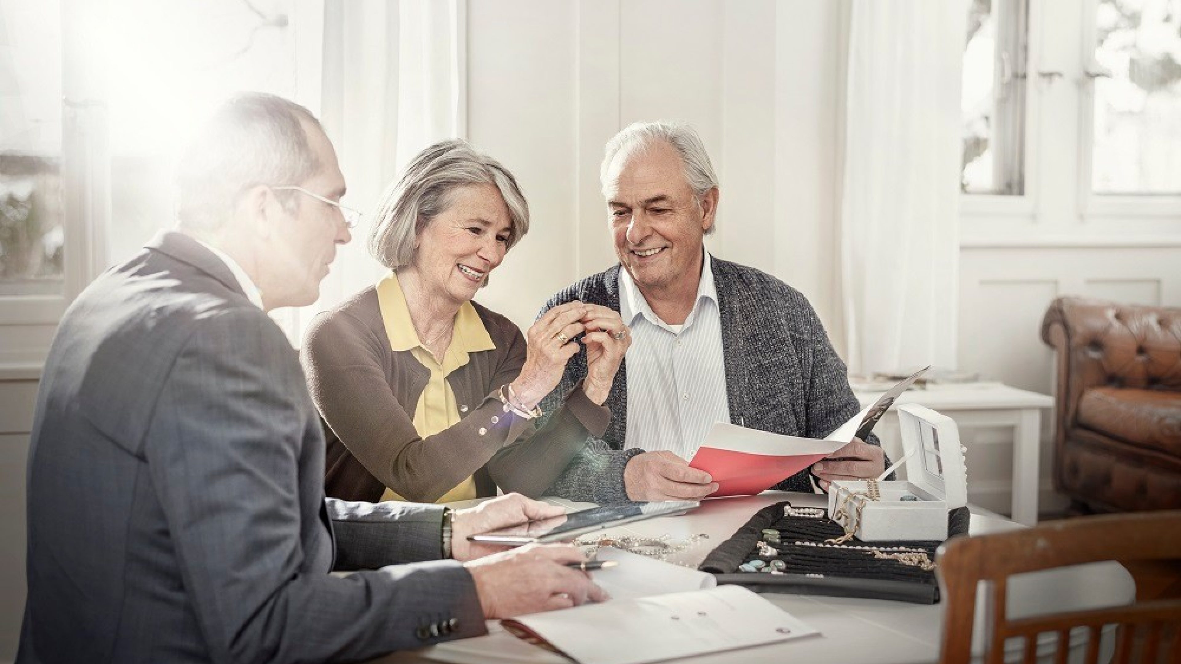 An elderly couple sits at the table with a consultant..