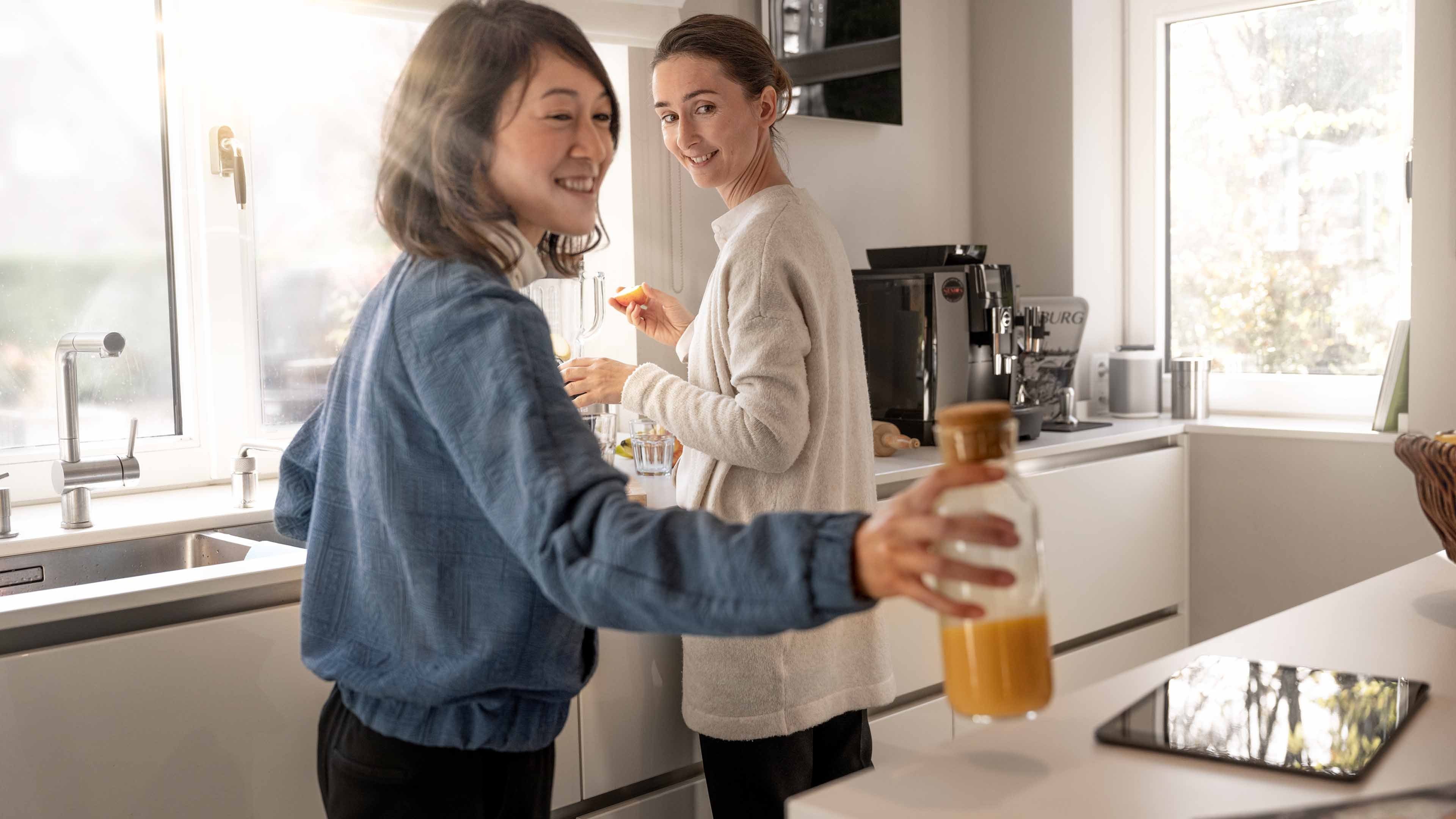 Two women making fresh orange juice in the kitchen.