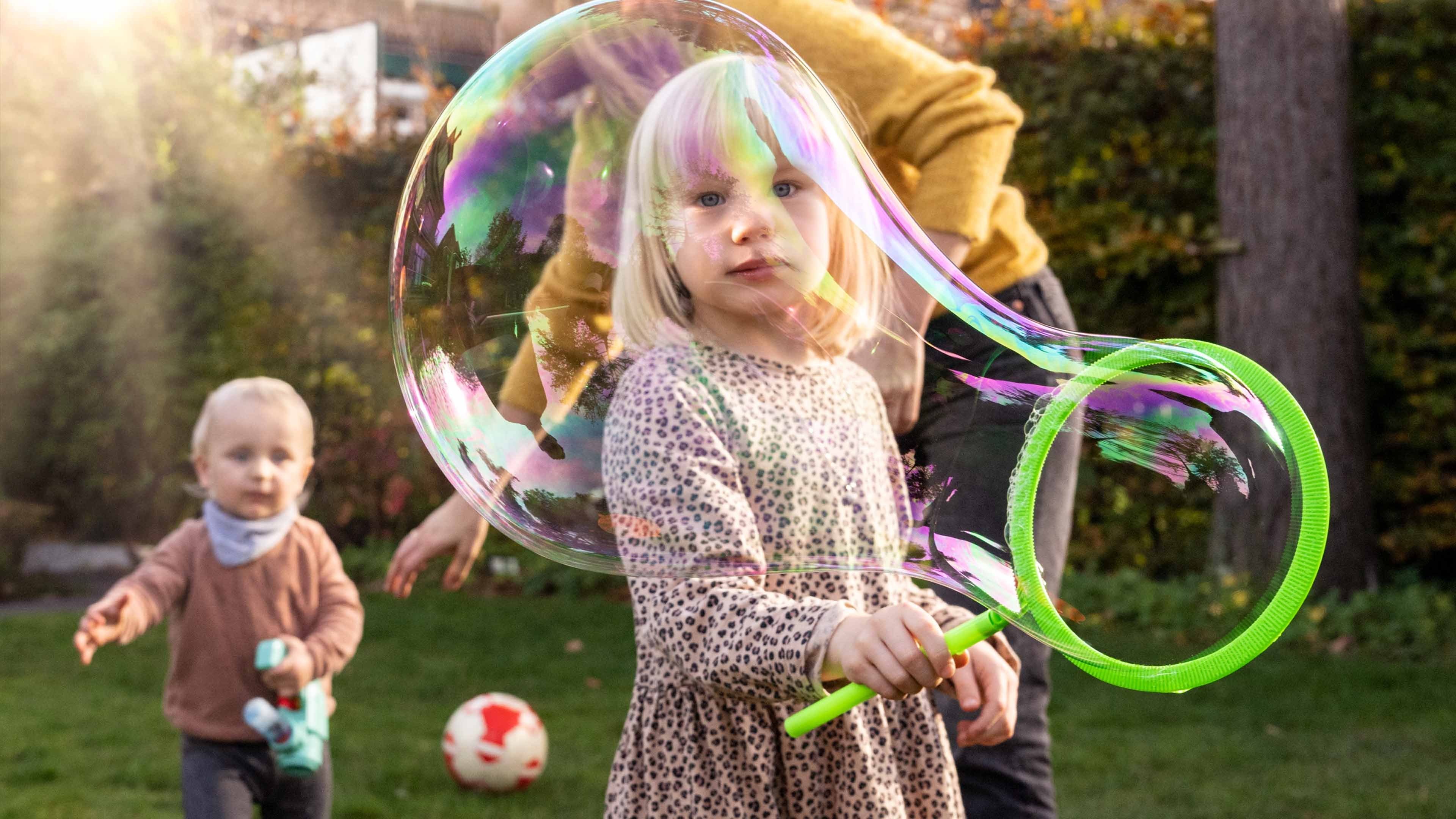 A girl and a small boy playing with soap bubbles