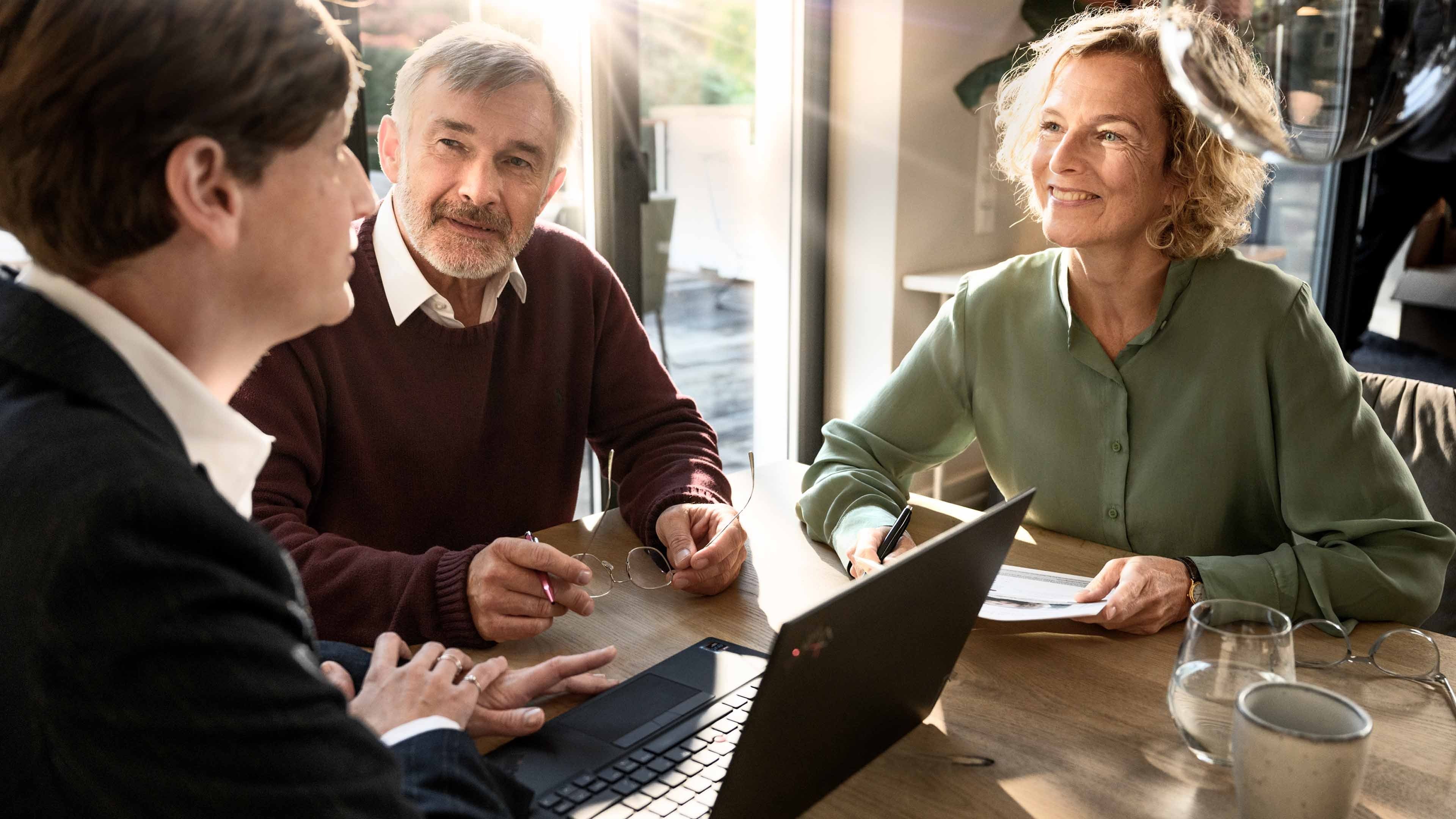 A man and a woman in a living room talking to a pensions advisor