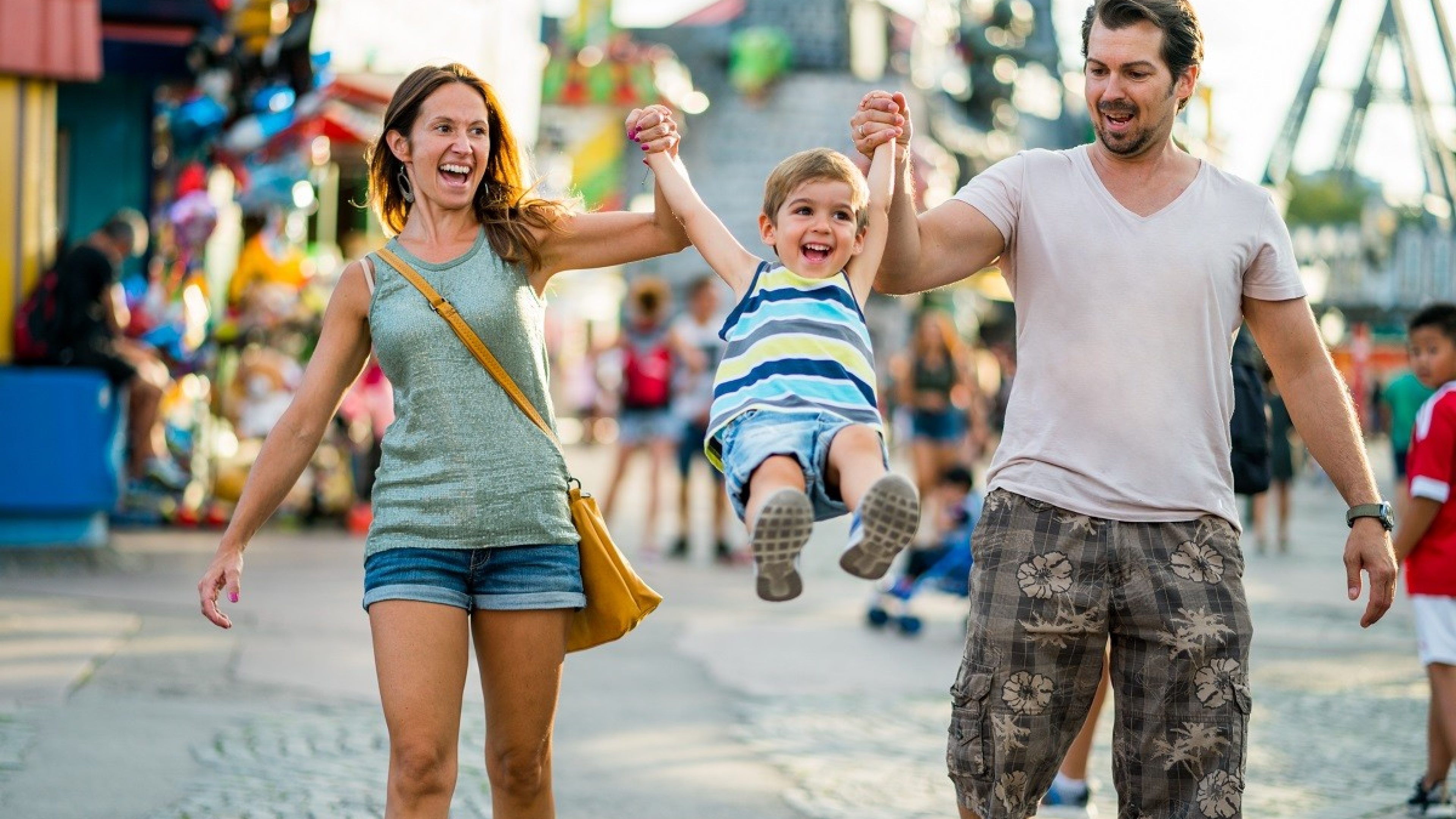 three years old boy with happy smiling mom and dad having fun on summer vacation day in themepark