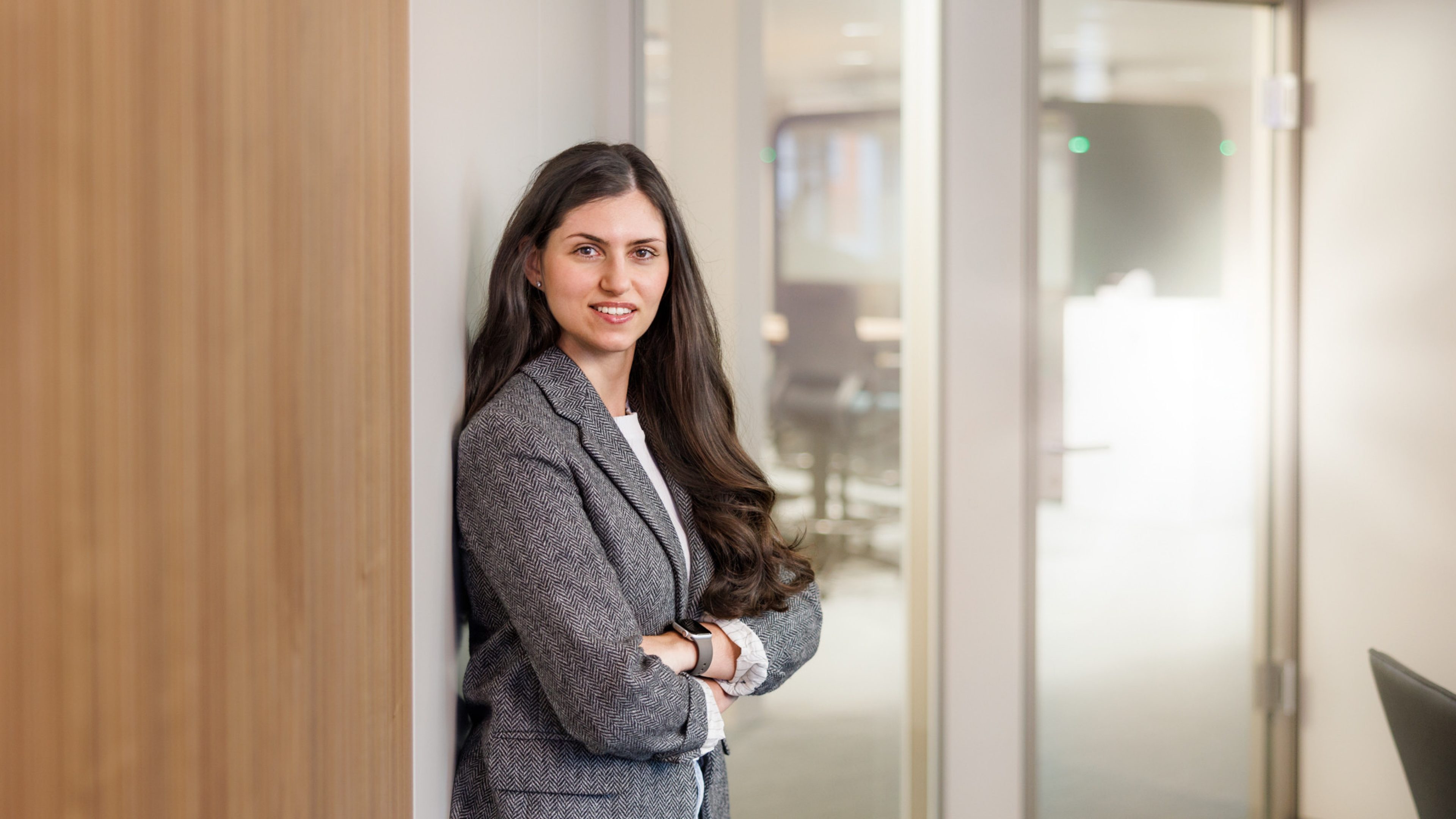 Female Swiss Life employee in a modern office, smiling at the camera.