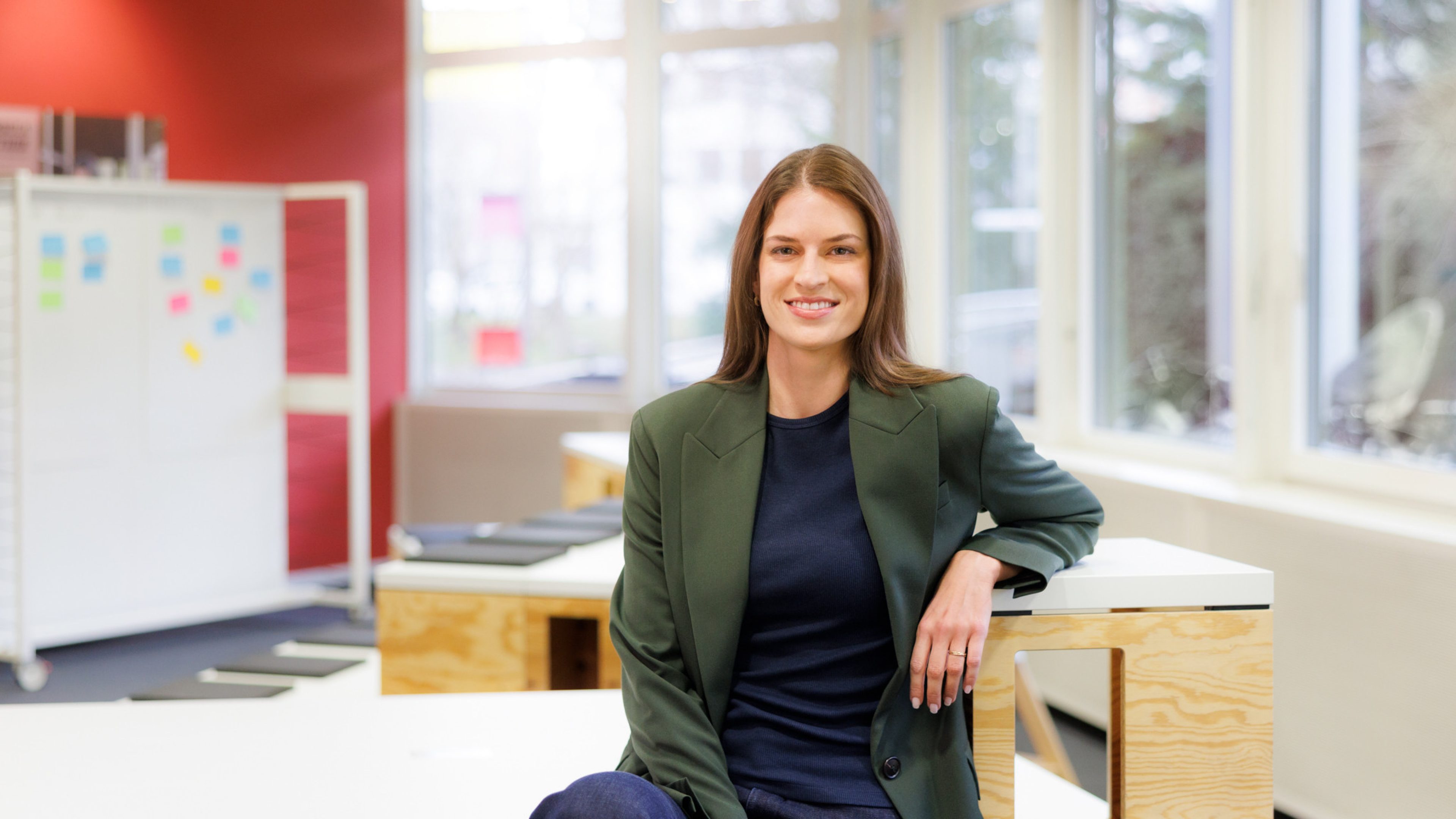 Female Swiss Life employee in a modern office, smiling at the camera.