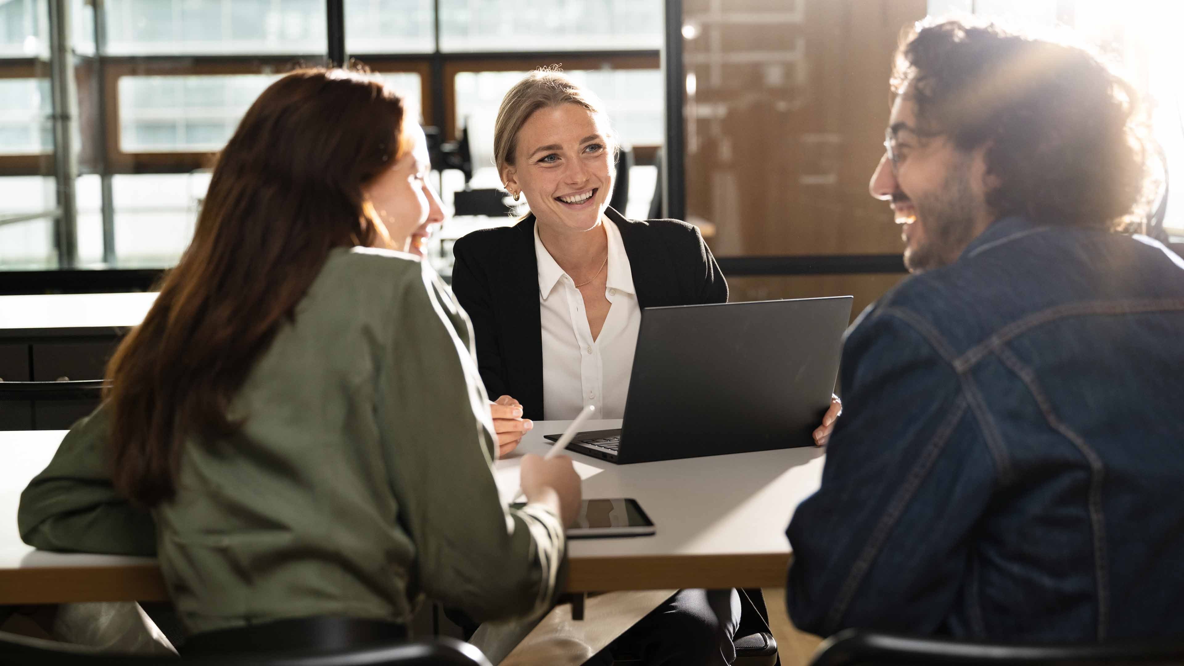 A Swiss Life advisor smiles as she advises a young couple in a personal customer consultation.