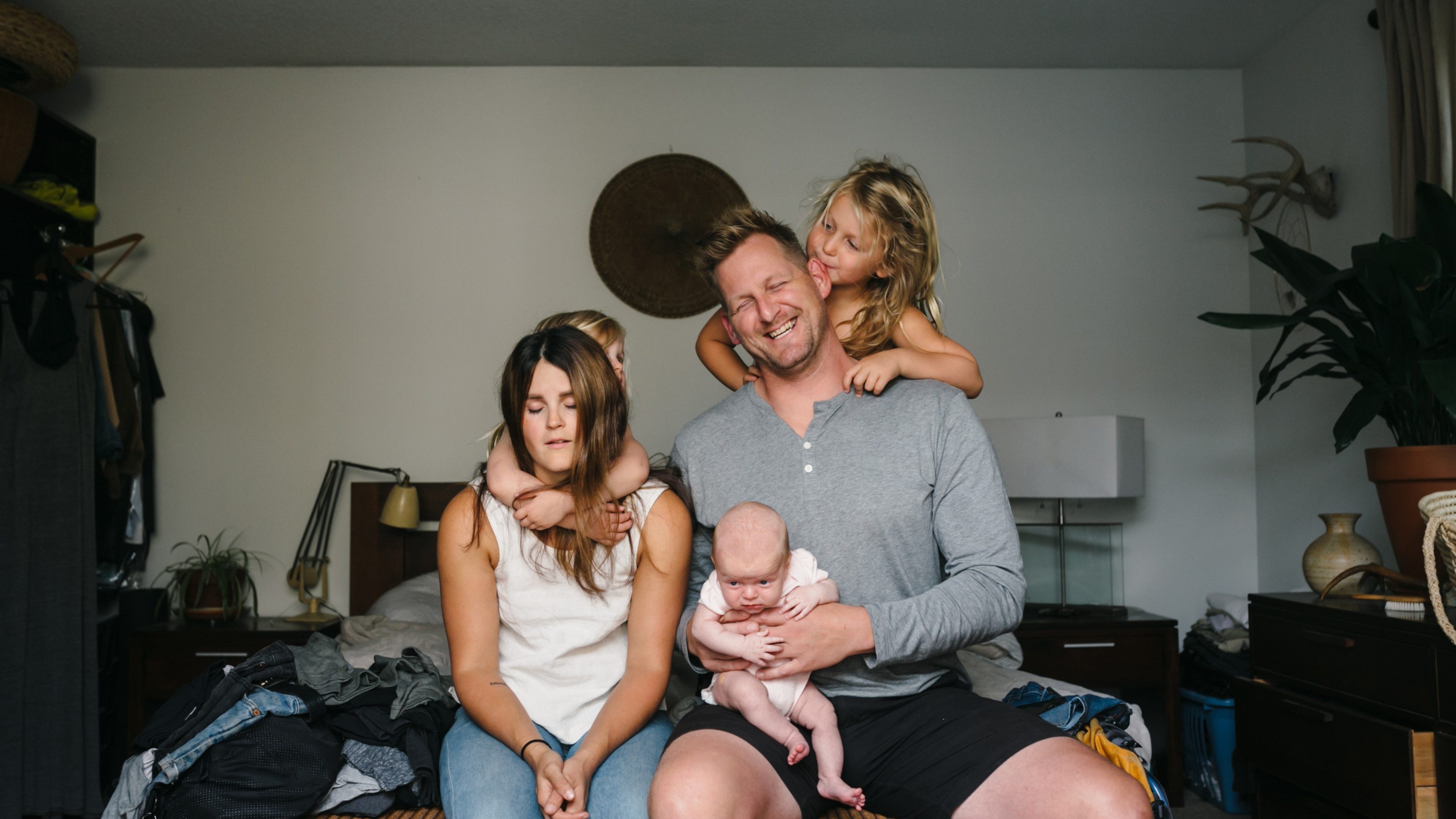 Young family with three kids, newborn baby and stressed out, laughing parents