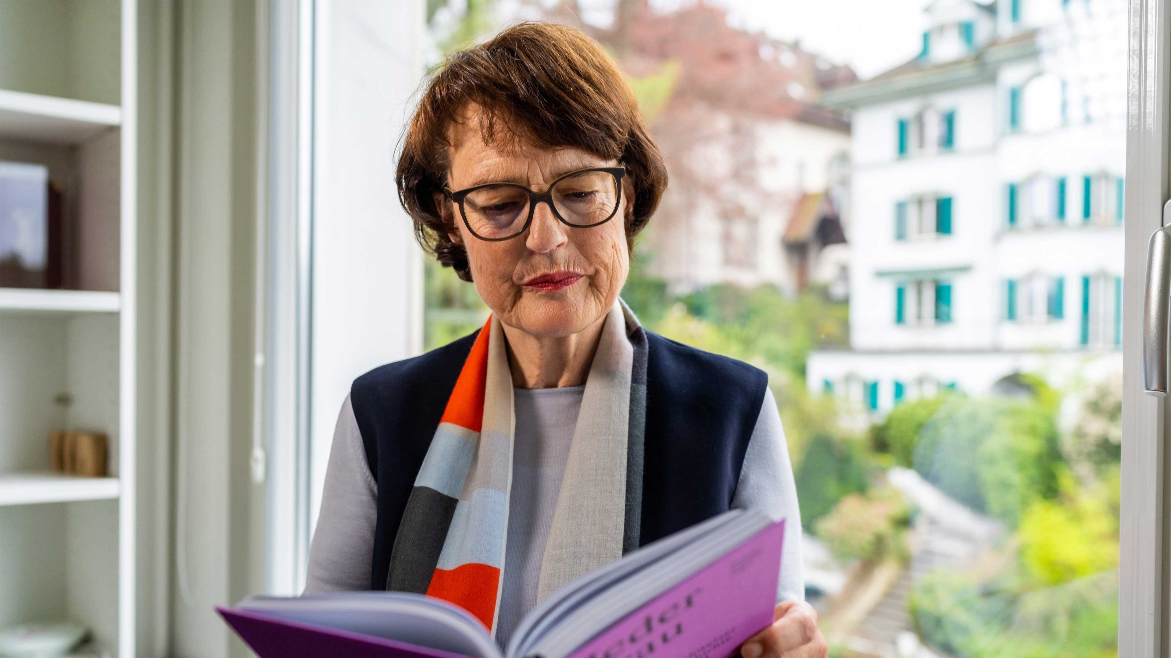 Femme avec lunettes devant une bibliothèque