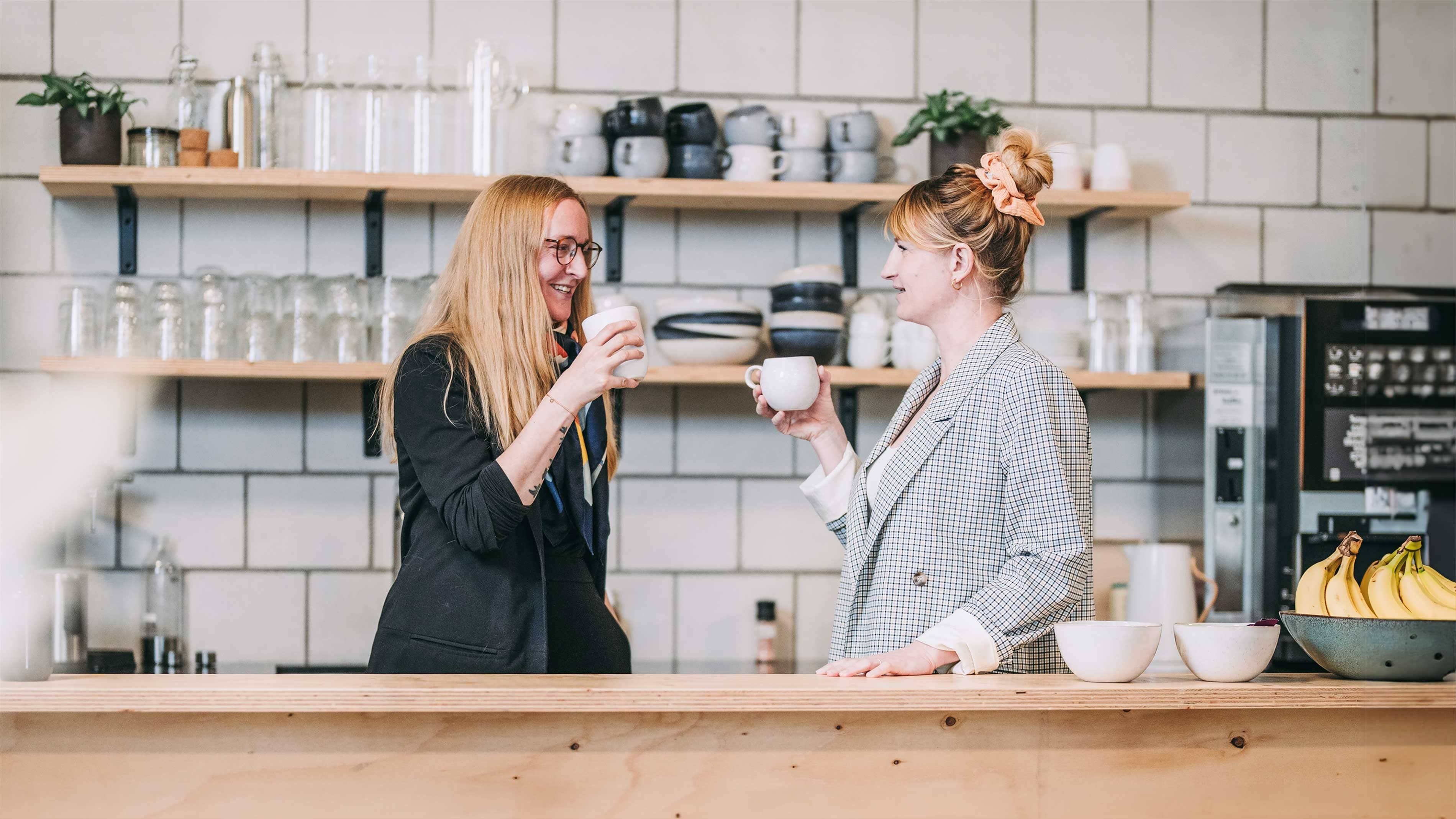 Deux femmes discutent dans une cuisine de bureau