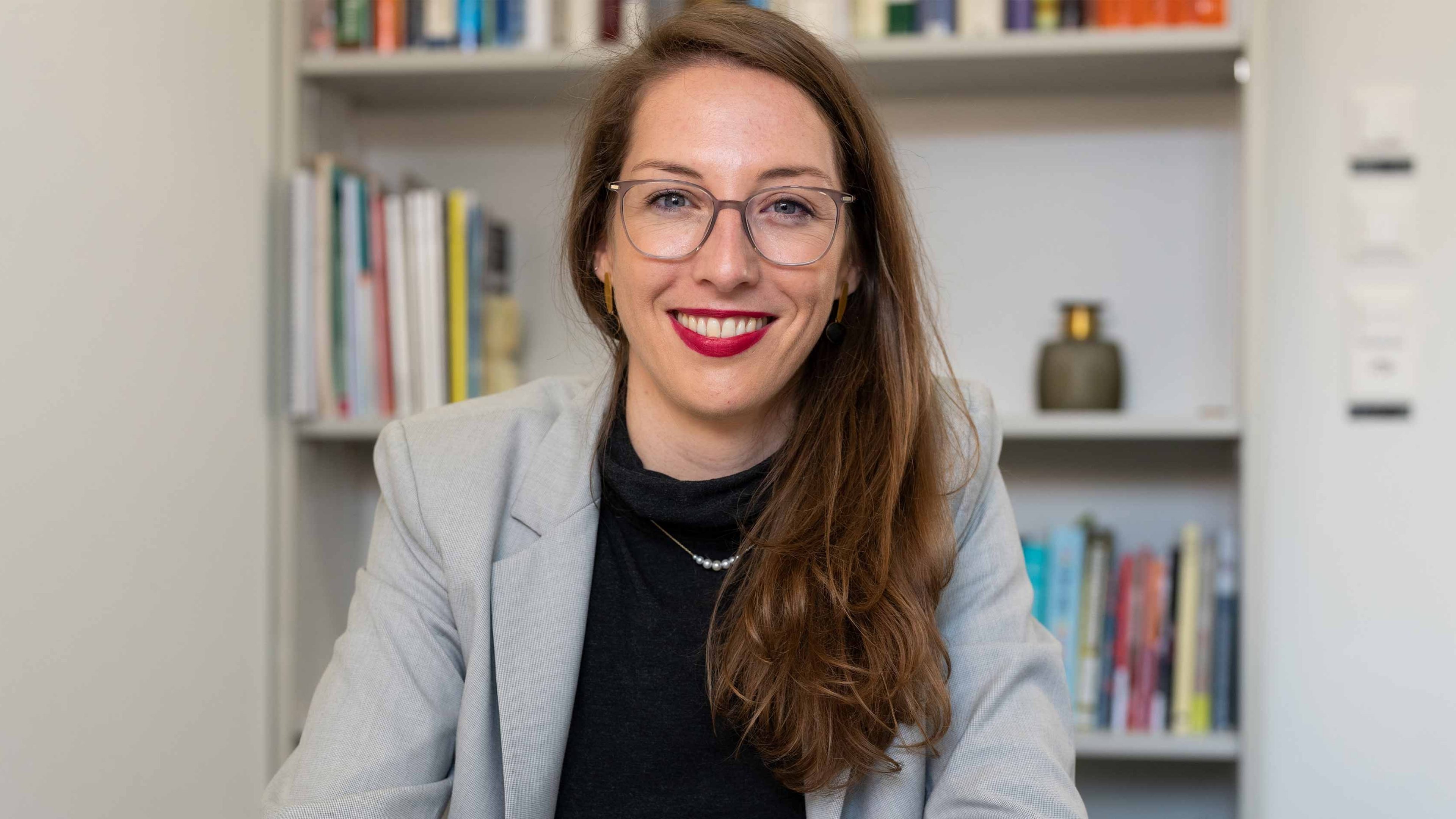 Femme avec lunettes devant une bibliothèque