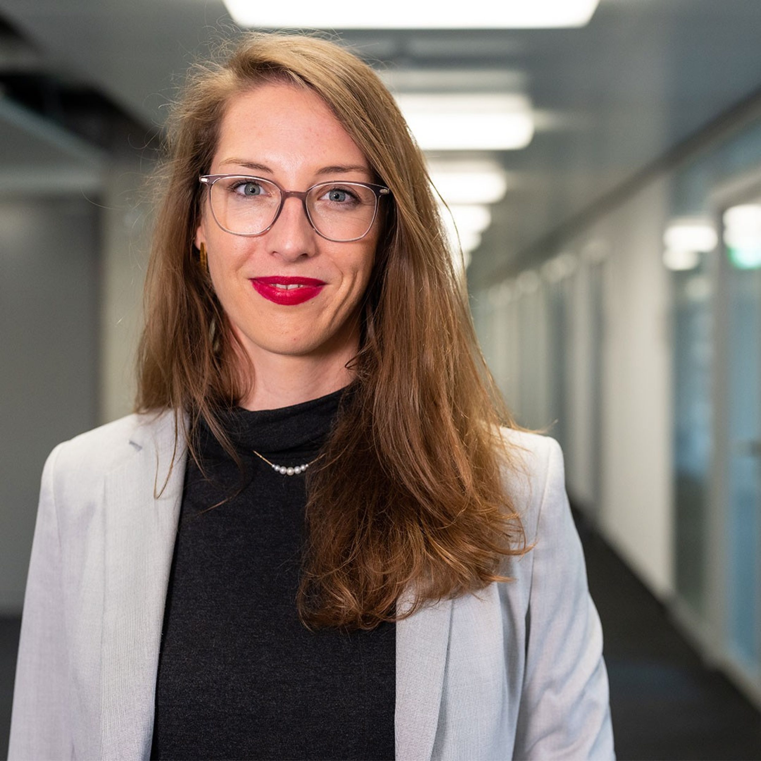 Frau in Büro lächelt in Kamera