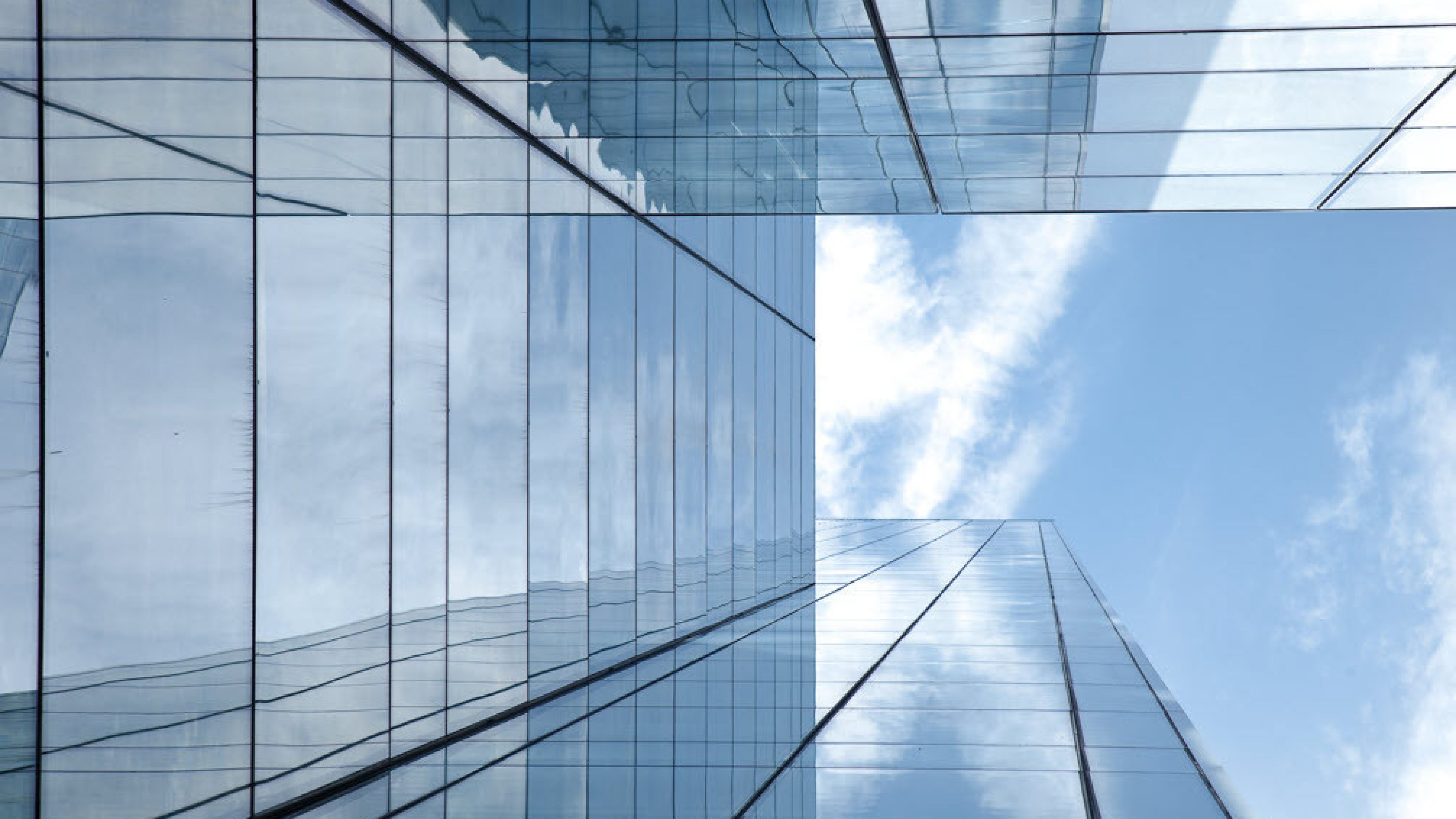 Vue le long d’une façade vitrée gris-bleu d’un immeuble, vers le ciel